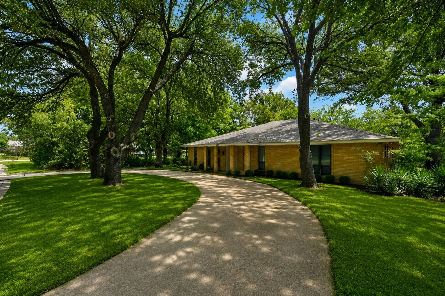 Ranch-style residence featuring a yellow brick exterior and a grey shingled roof