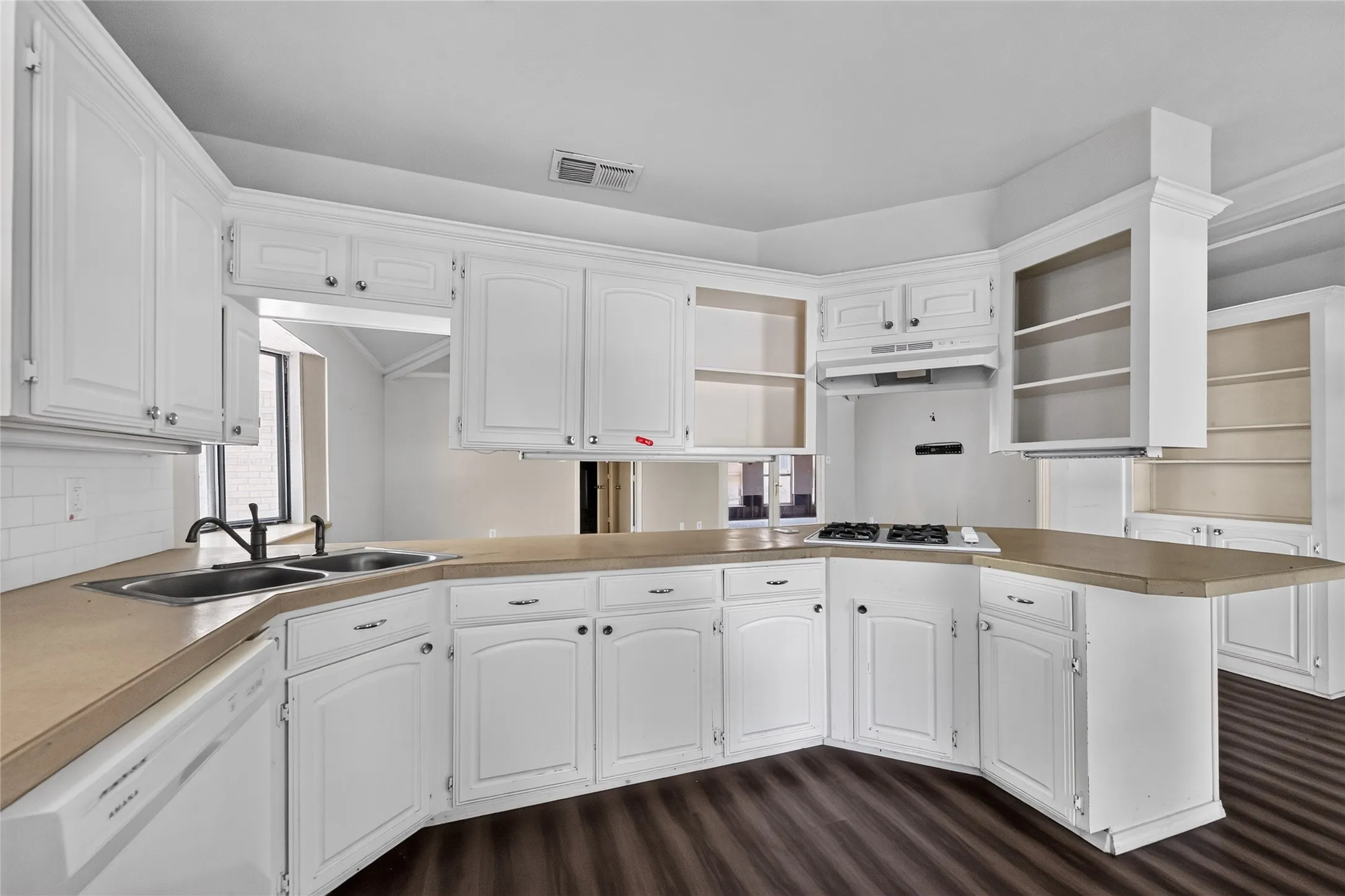 Kitchen featuring white cabinetry, light-toned countertops, a double basin sink with a dark-finish faucet, a stovetop, and wood-finish flooring