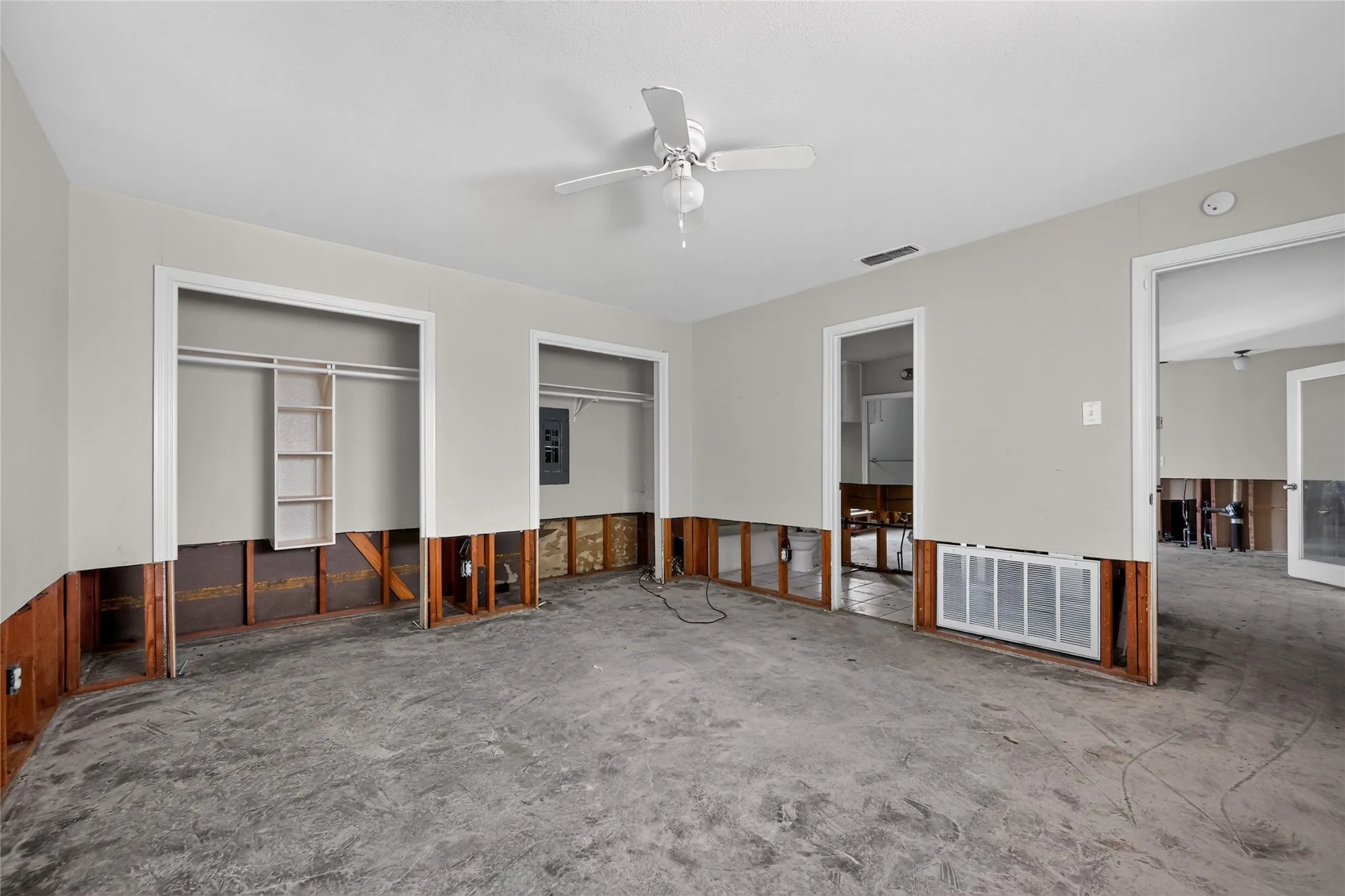 Interior space featuring a ceiling fan, exposed wall framing, and a concrete subfloor