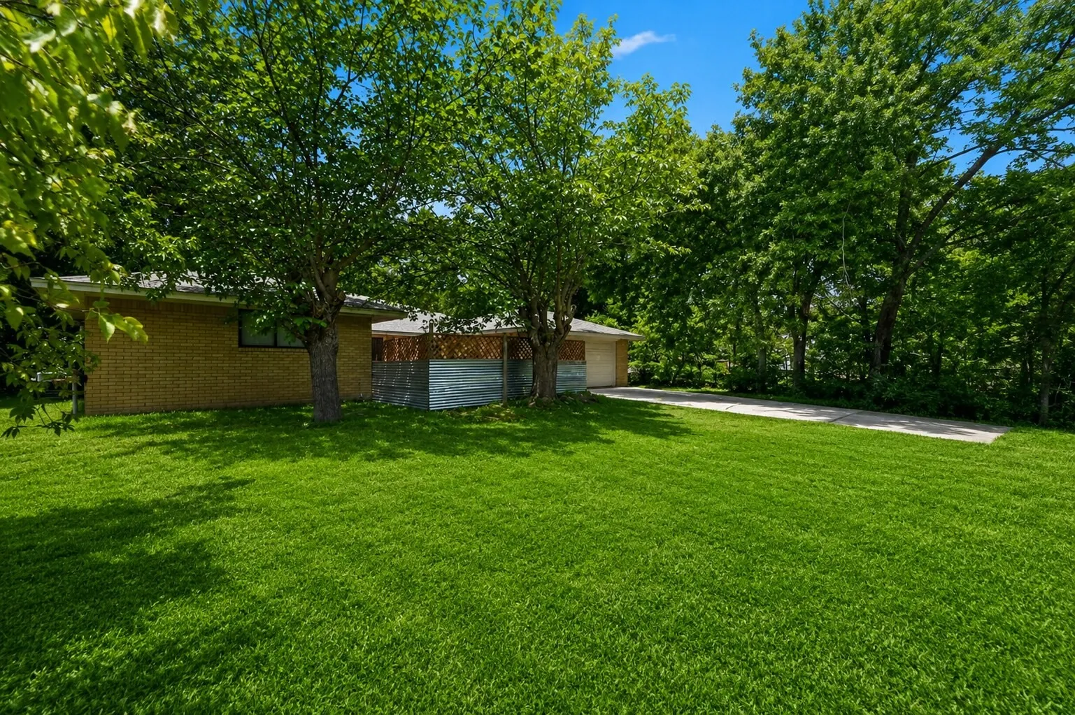 Expansive front lawn with mature trees providing natural shade