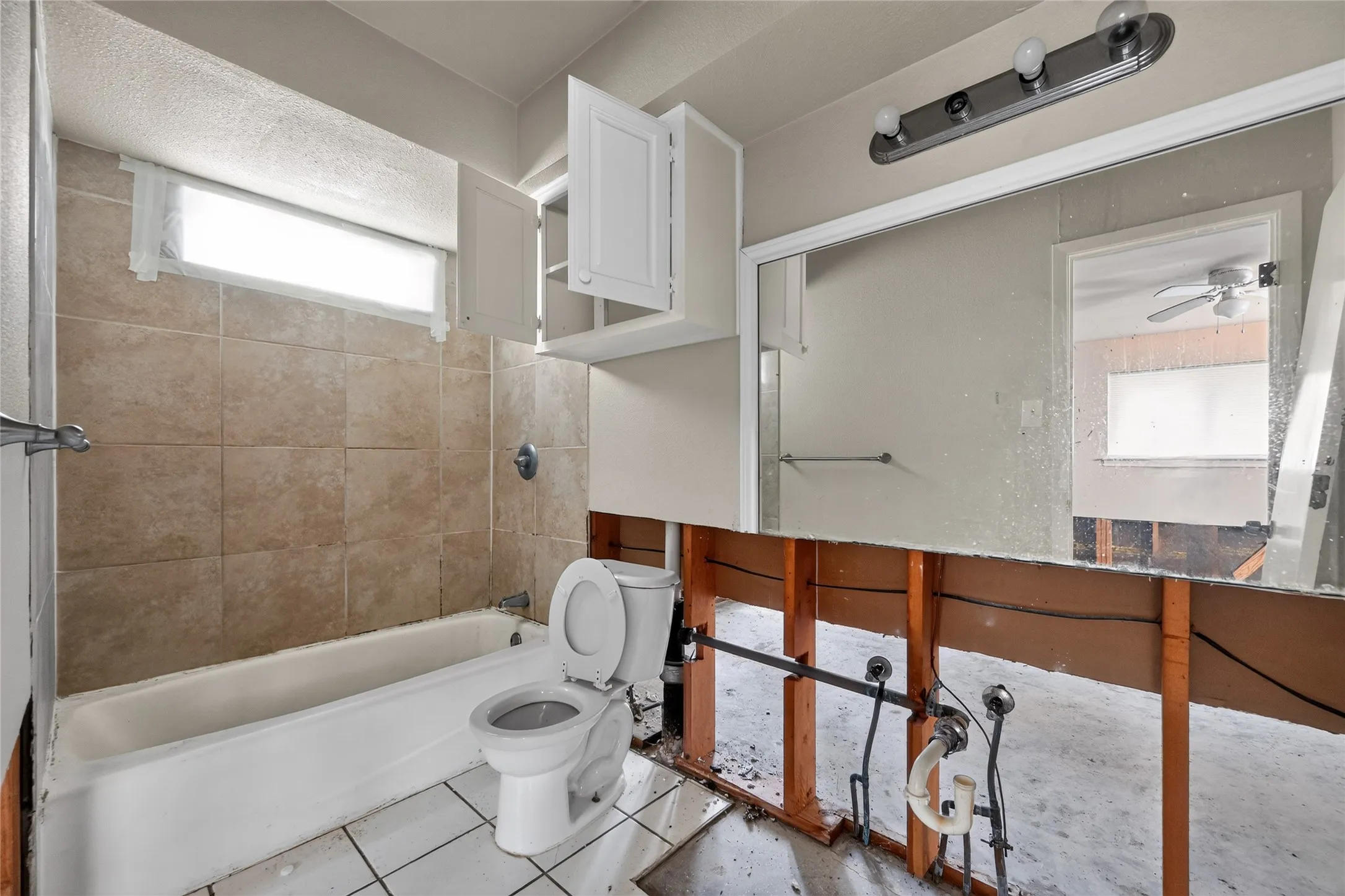 Bathroom featuring a white bathtub, ceramic wall tiling, and a window for natural light