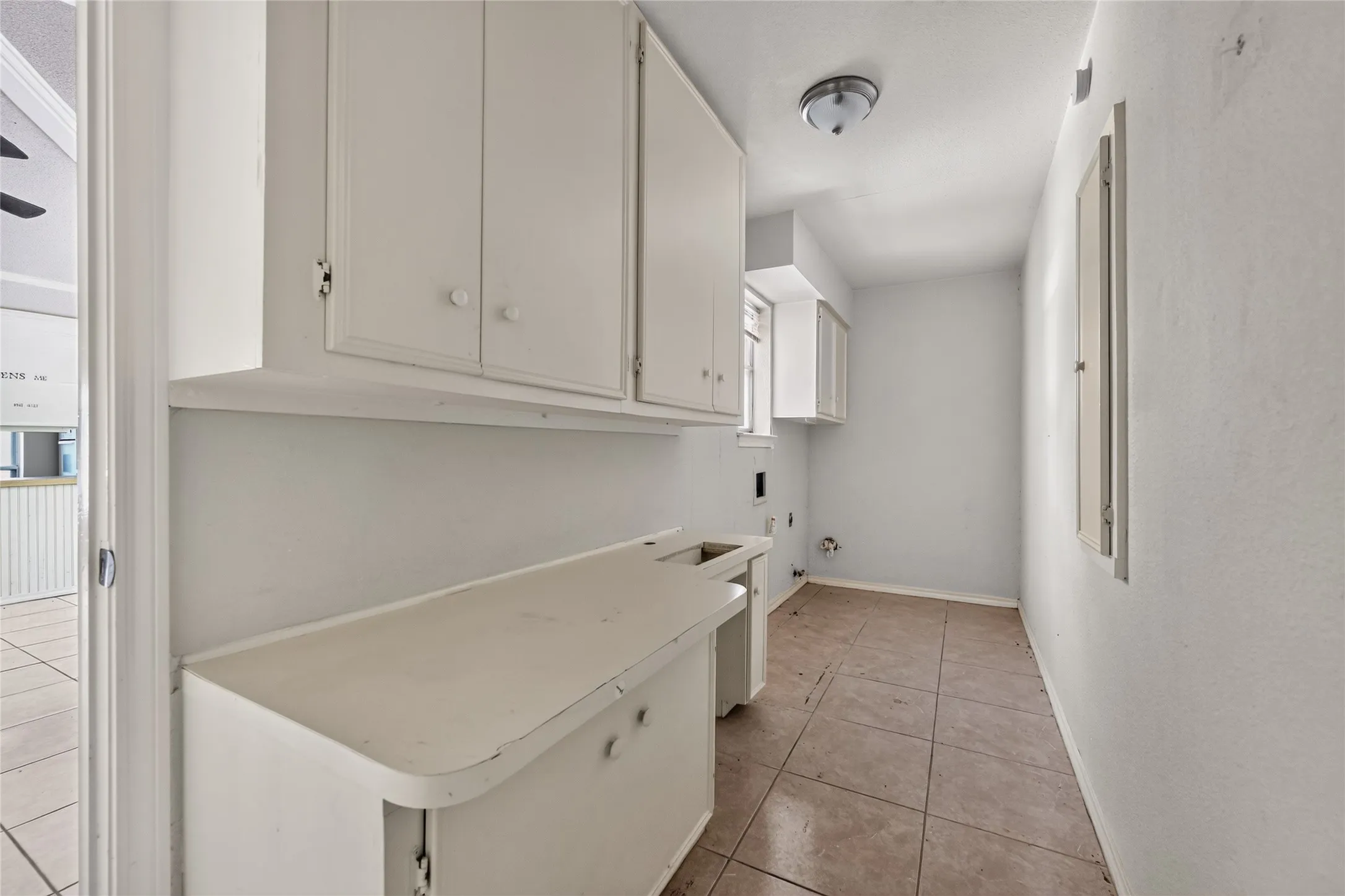 Utility area with tile flooring, white cabinetry, integrated countertop, and an overhead light fixture