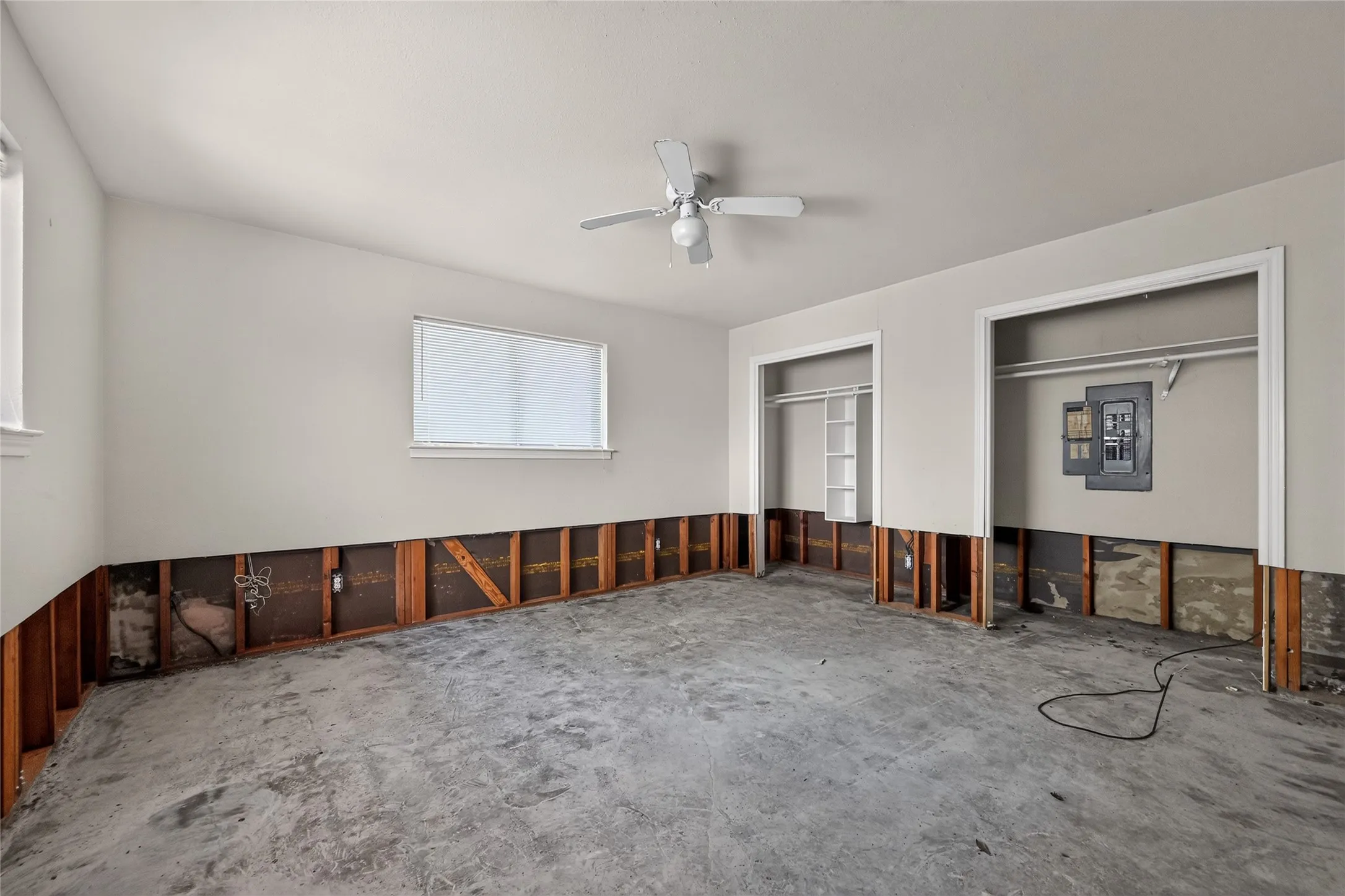 Room with exposed lower wall framing, two windows, and two closet openings