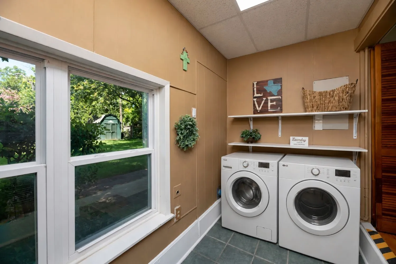 Virtually Staged-Dedicated laundry space with two front-loading machines, built-in shelving, and tile flooring