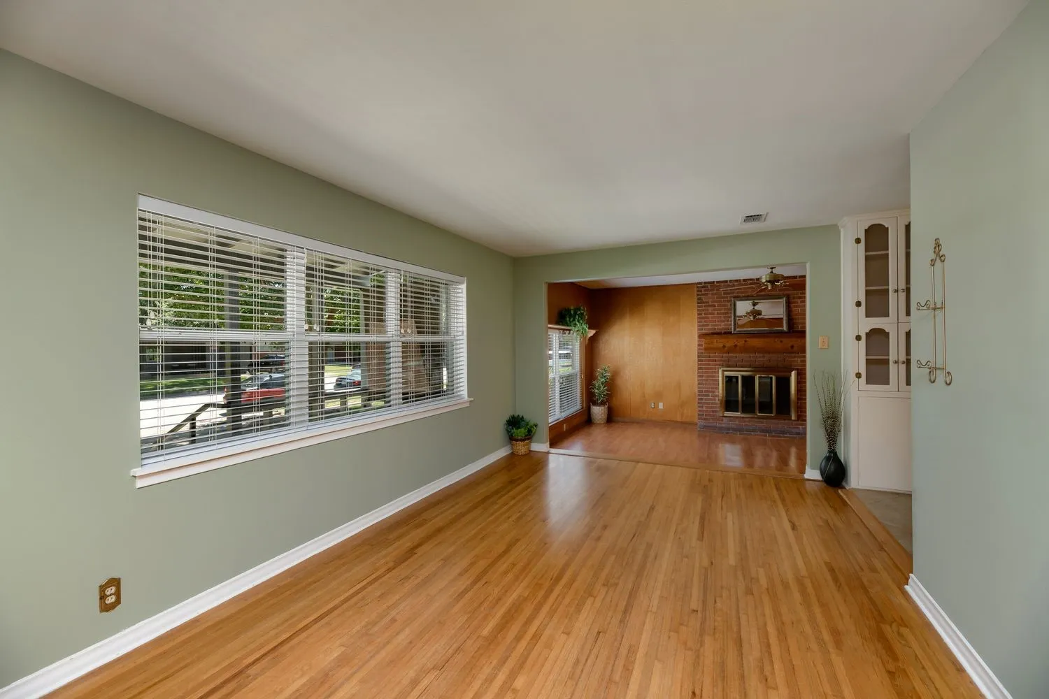 Hardwood flooring extends throughout the space, complemented by a large window with white blinds