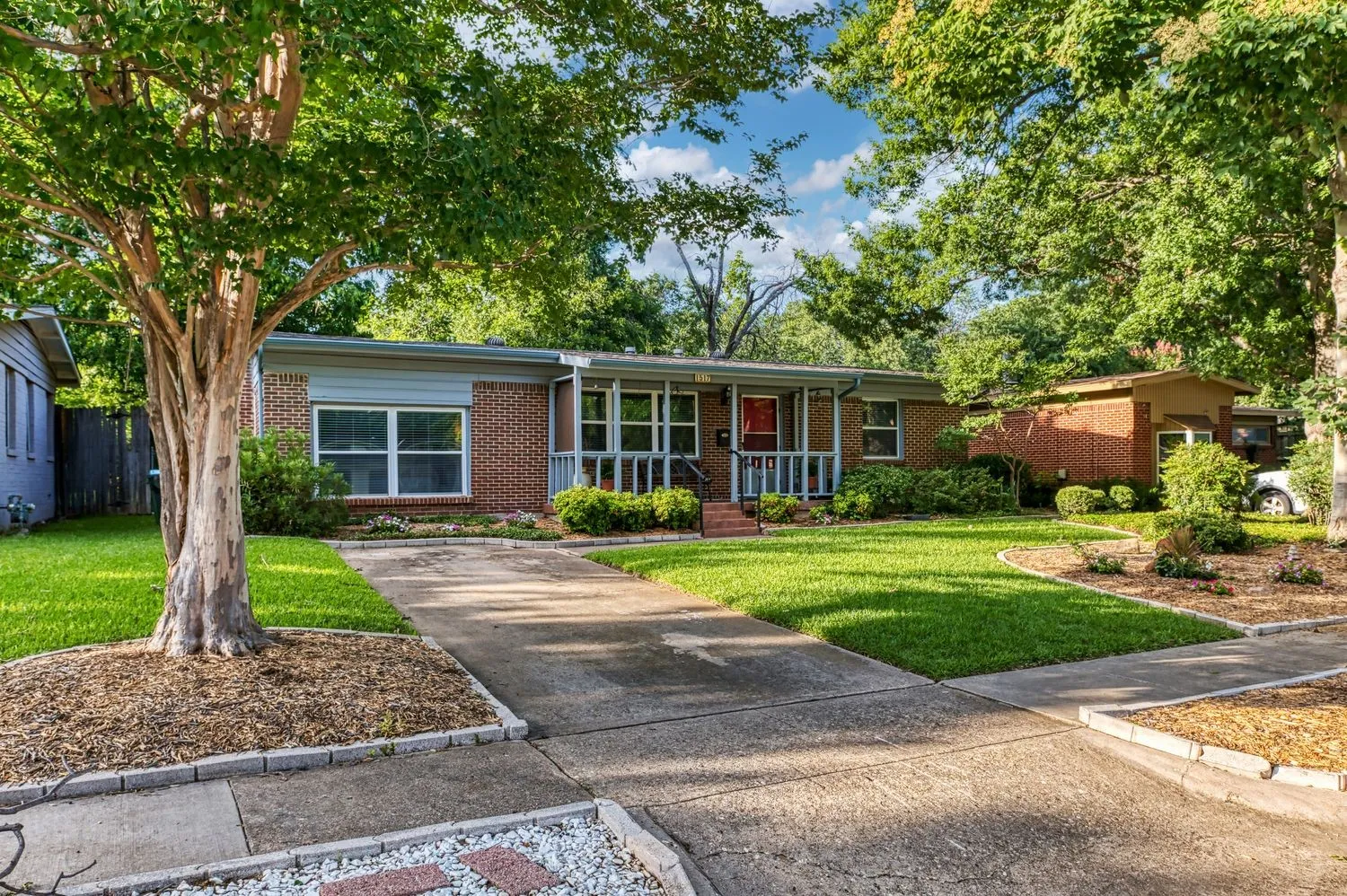 Shaded front yard with established landscaping and generous driveway parking.
