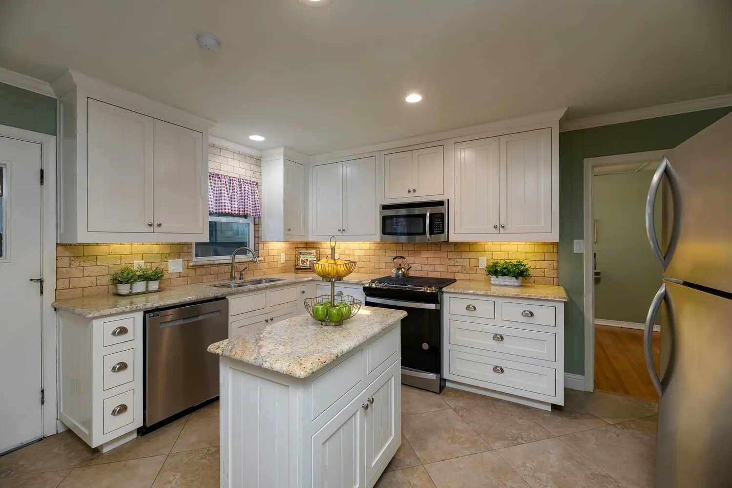 Kitchen featuring a center island, white cabinetry, granite countertops, tile flooring, and stainless steel appliances