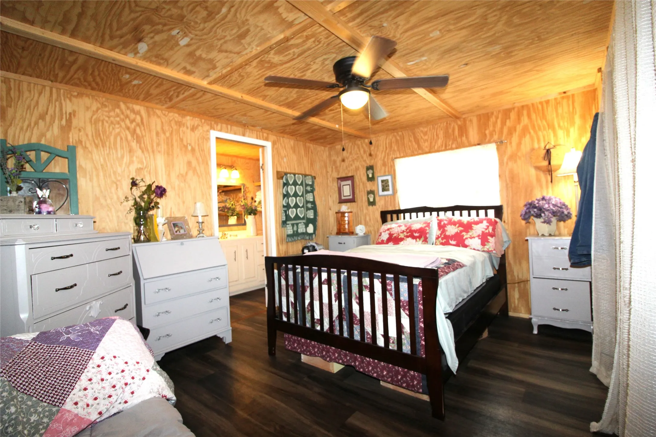 Interior room featuring wood-finish walls and ceiling, dark wood-finish flooring, a ceiling fan with integrated lighting, and a white framed doorway