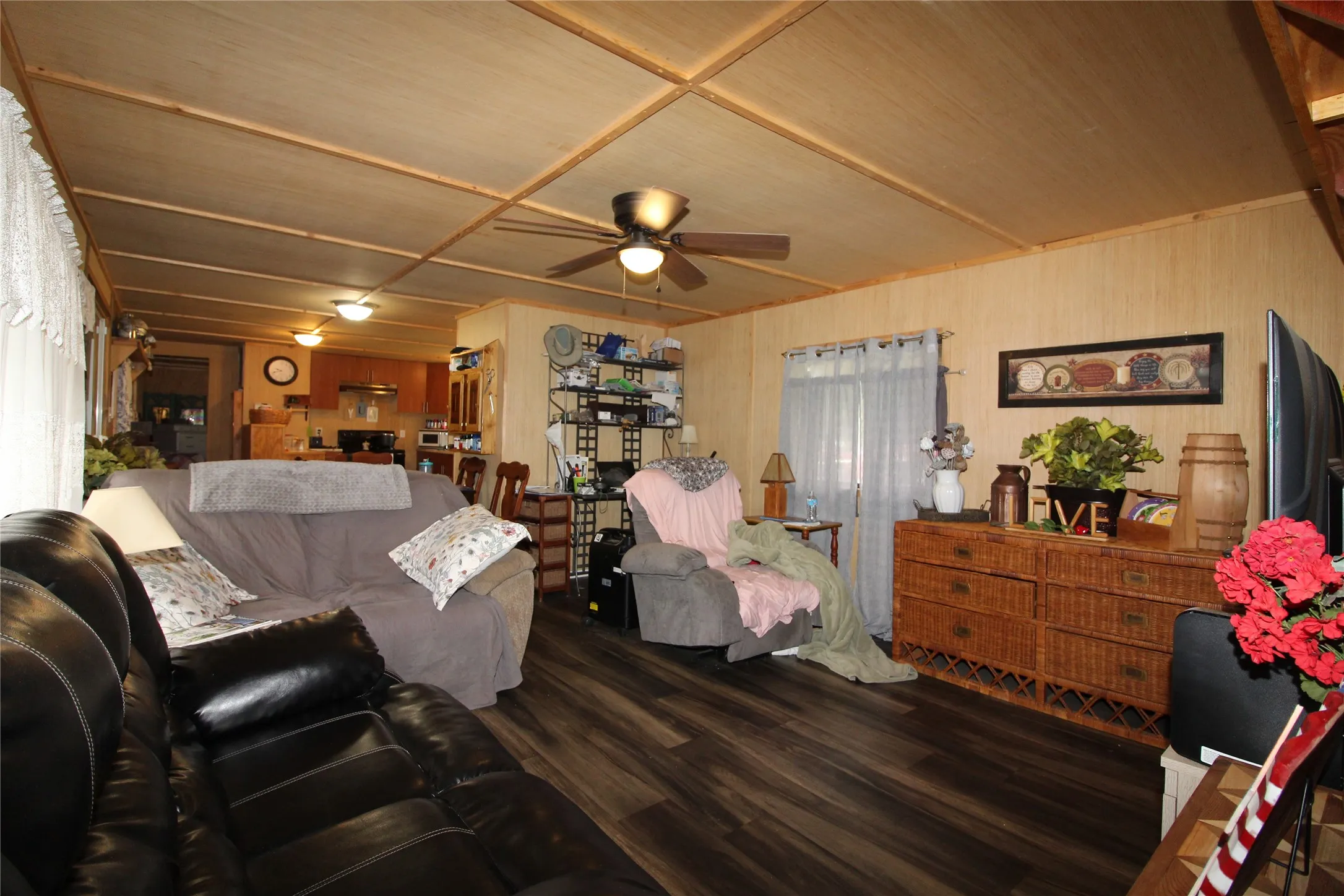 Spacious living area featuring wood-finish flooring, paneled walls, and a wood-paneled ceiling with exposed beams