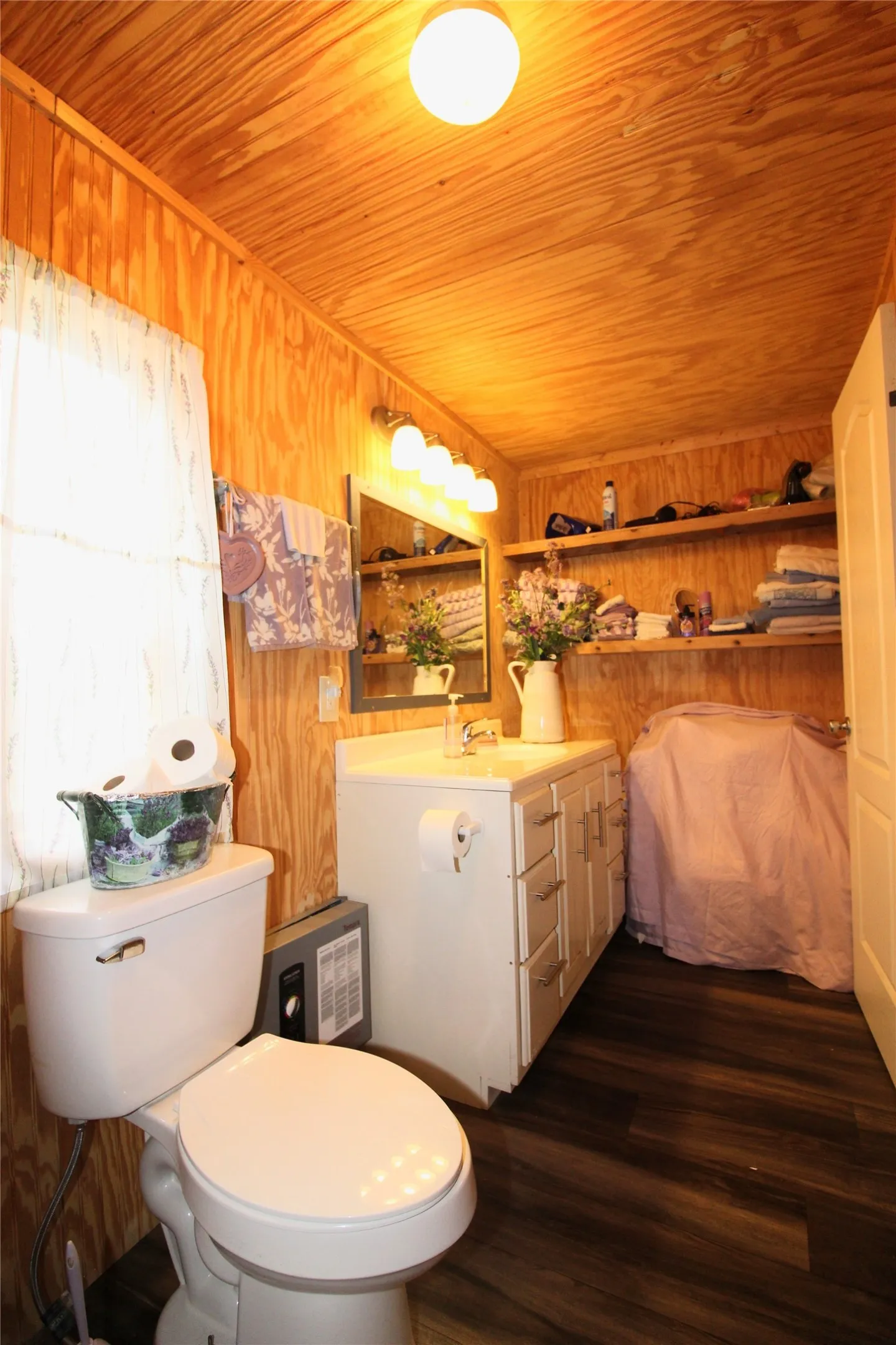 Wood-paneled walls and ceiling in this bathroom featuring dark wood-finish flooring