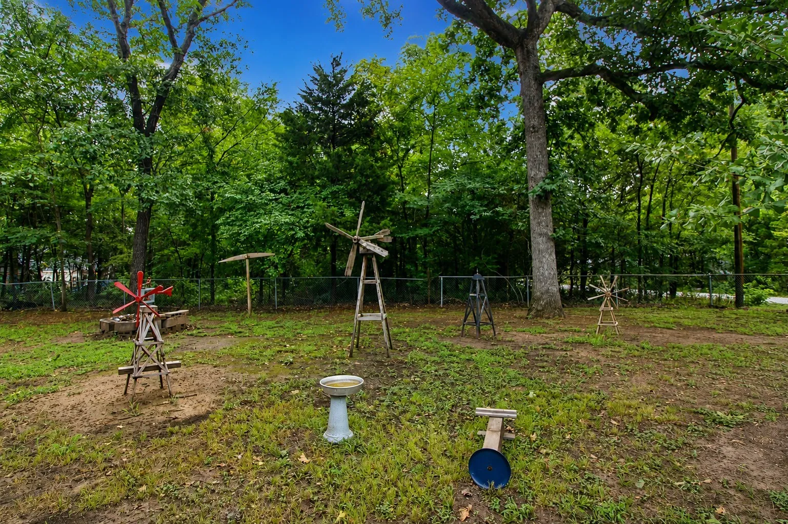 Expansive green space featuring a variety of mature trees and a perimeter fence