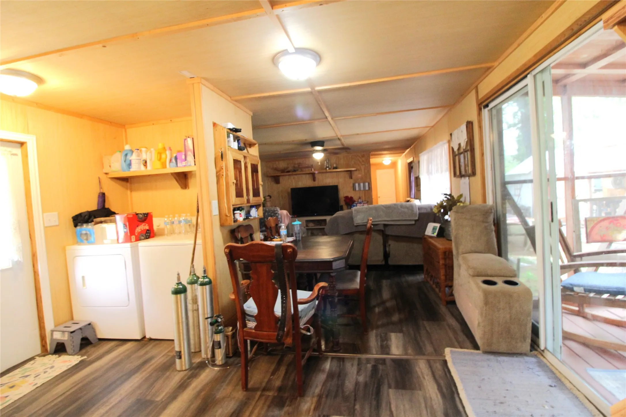 Open-concept living area with wood-finish flooring, a built-in shelving unit, and a sliding glass door