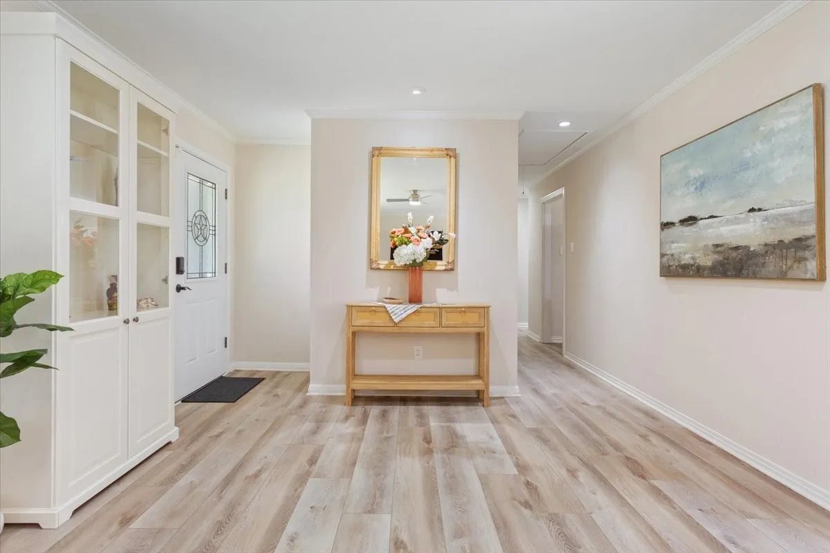 Entryway featuring wood-finish flooring, a white built-in cabinet with glass-front doors, and a white entry door with decorative glass inlay