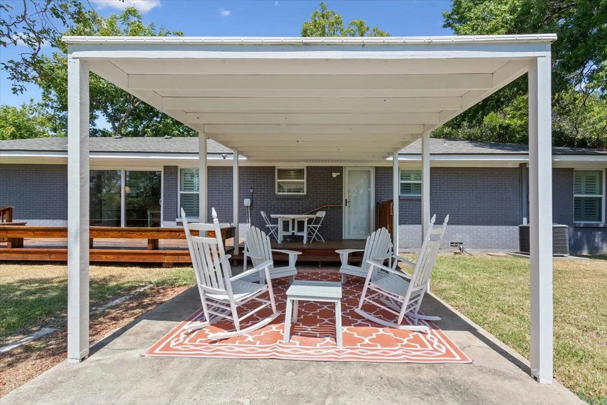 Covered patio with a concrete slab, a wooden deck, and a gray brick exterior