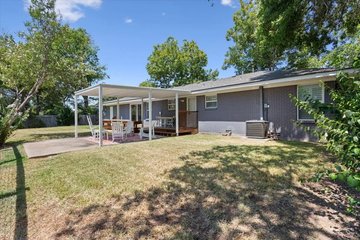 Expansive backyard featuring a covered patio, additional concrete patio, and a raised wood deck
