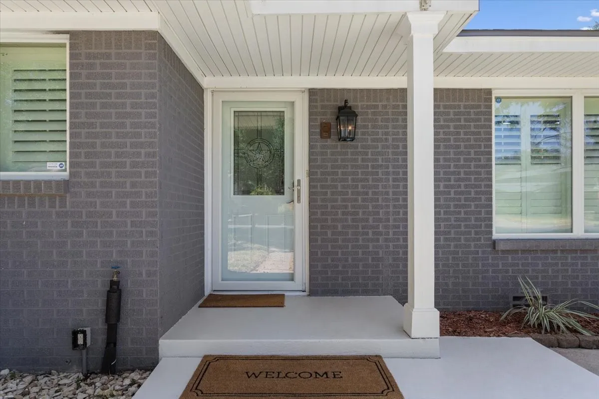 Gray brick exterior featuring white trim and a covered front entry