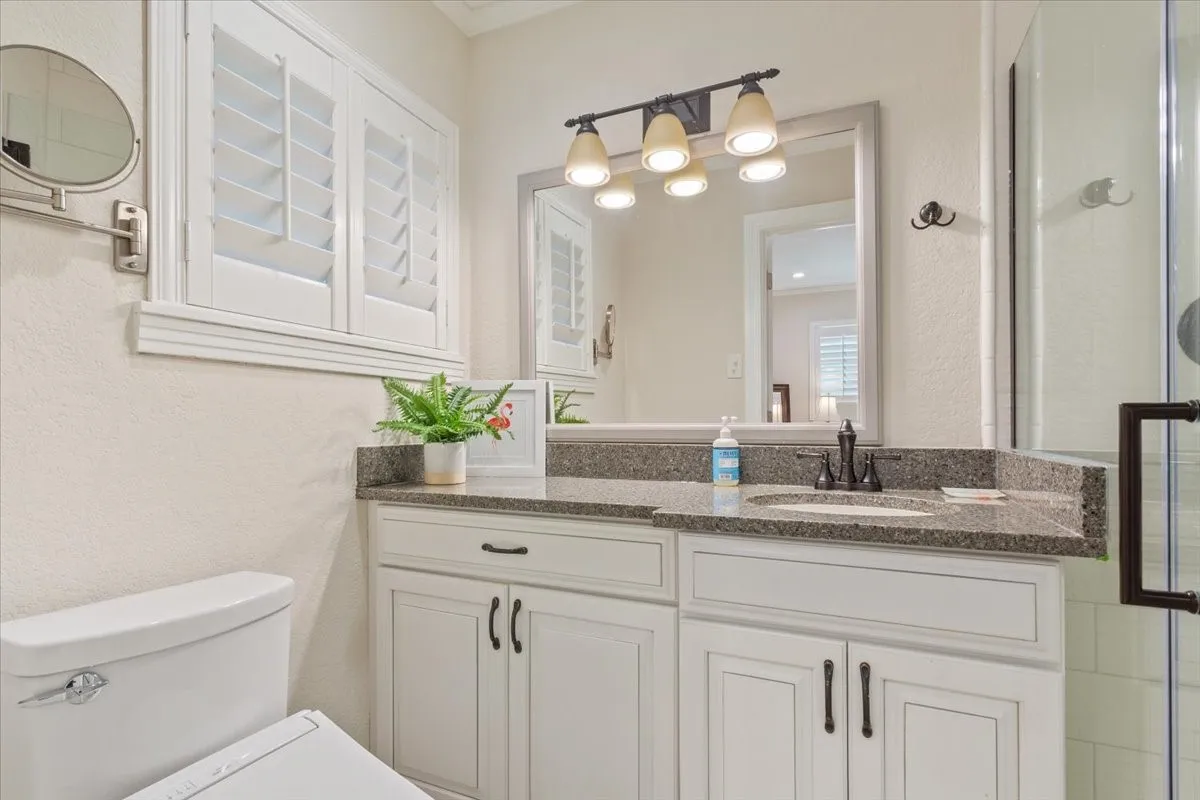 White cabinetry with dark hardware, a single undermount sink, and a speckled countertop