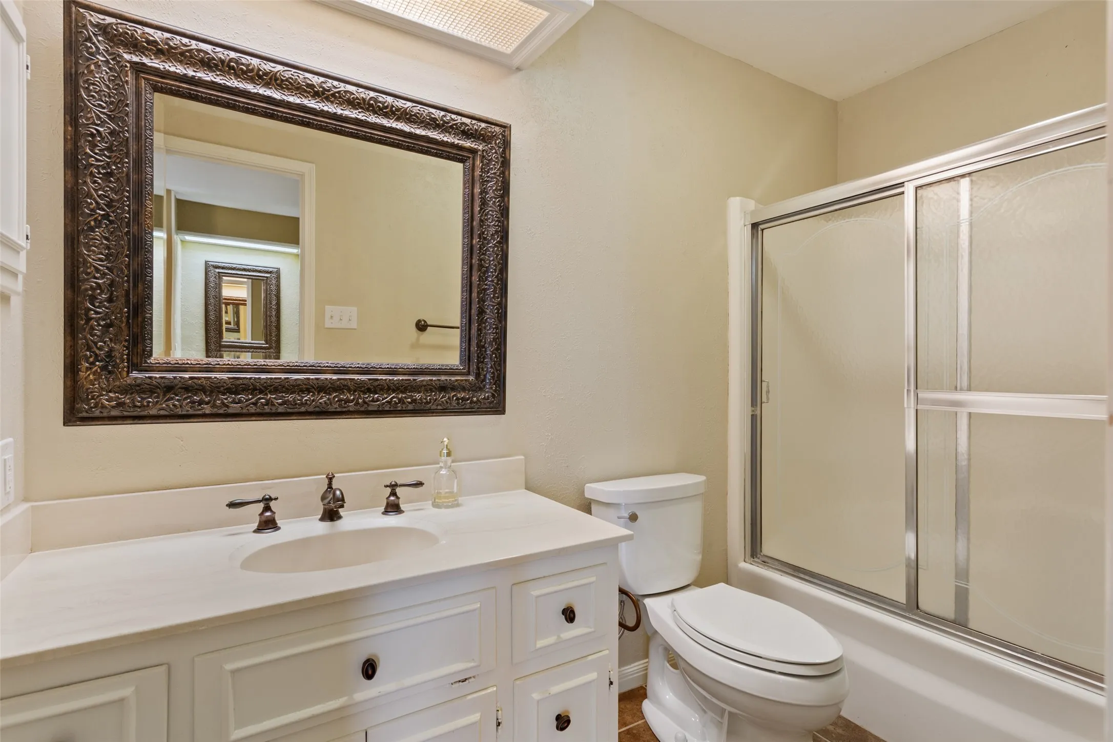 White vanity with dark hardware, undermount sink, and light-toned countertop