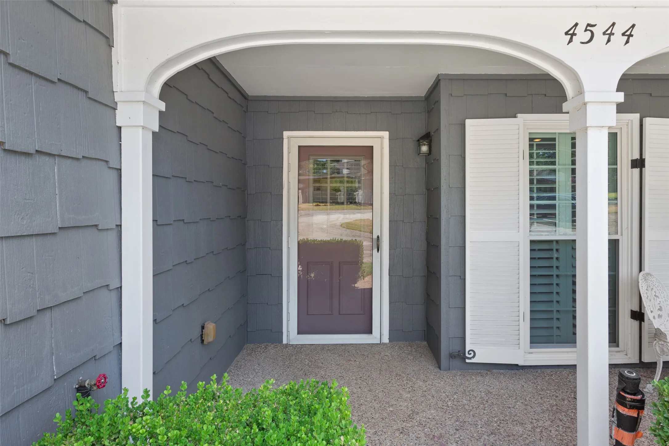 Arched entryway with a gray shingle exterior