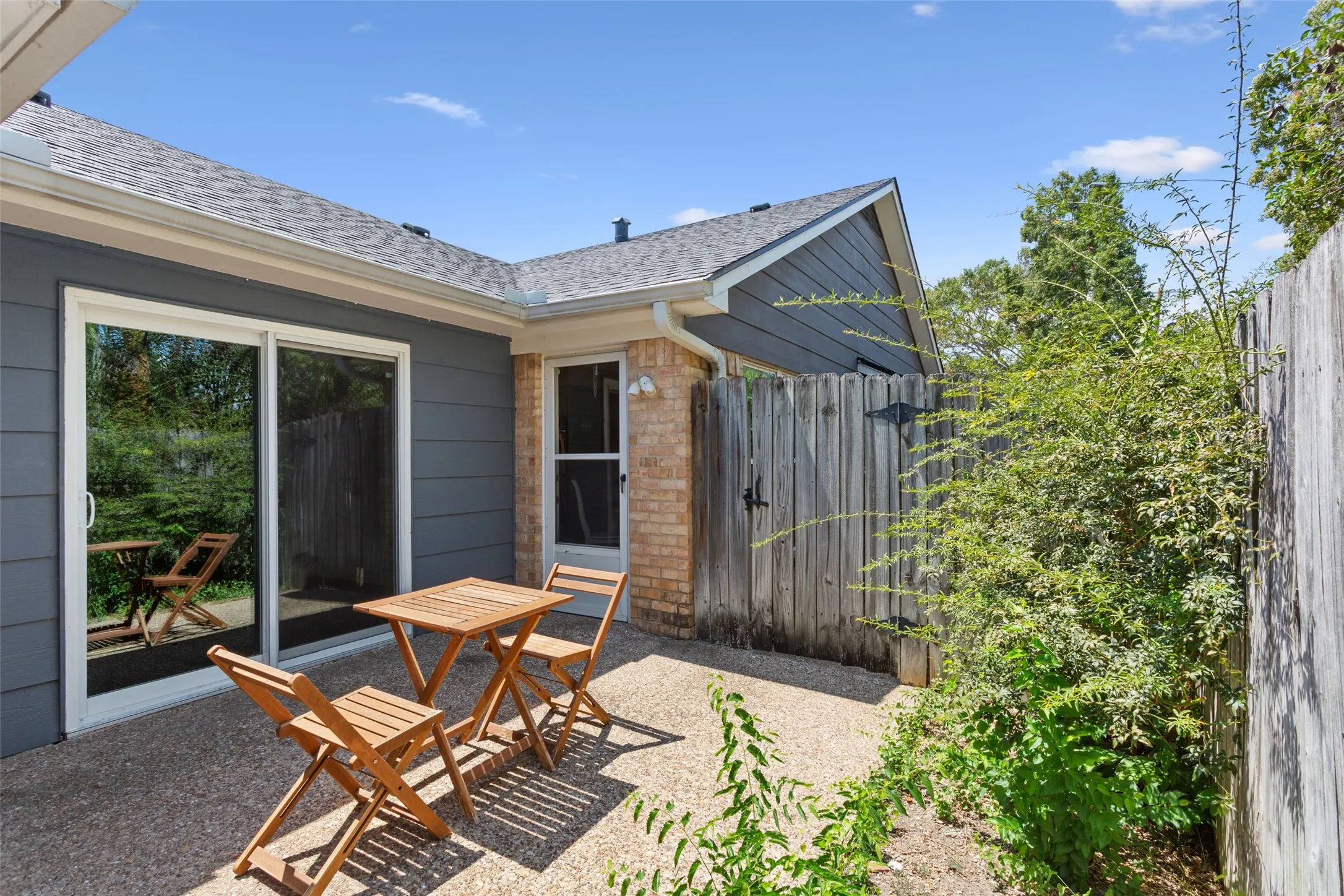 Patio area with a gravel surface, wood privacy fencing, and mature perimeter landscaping