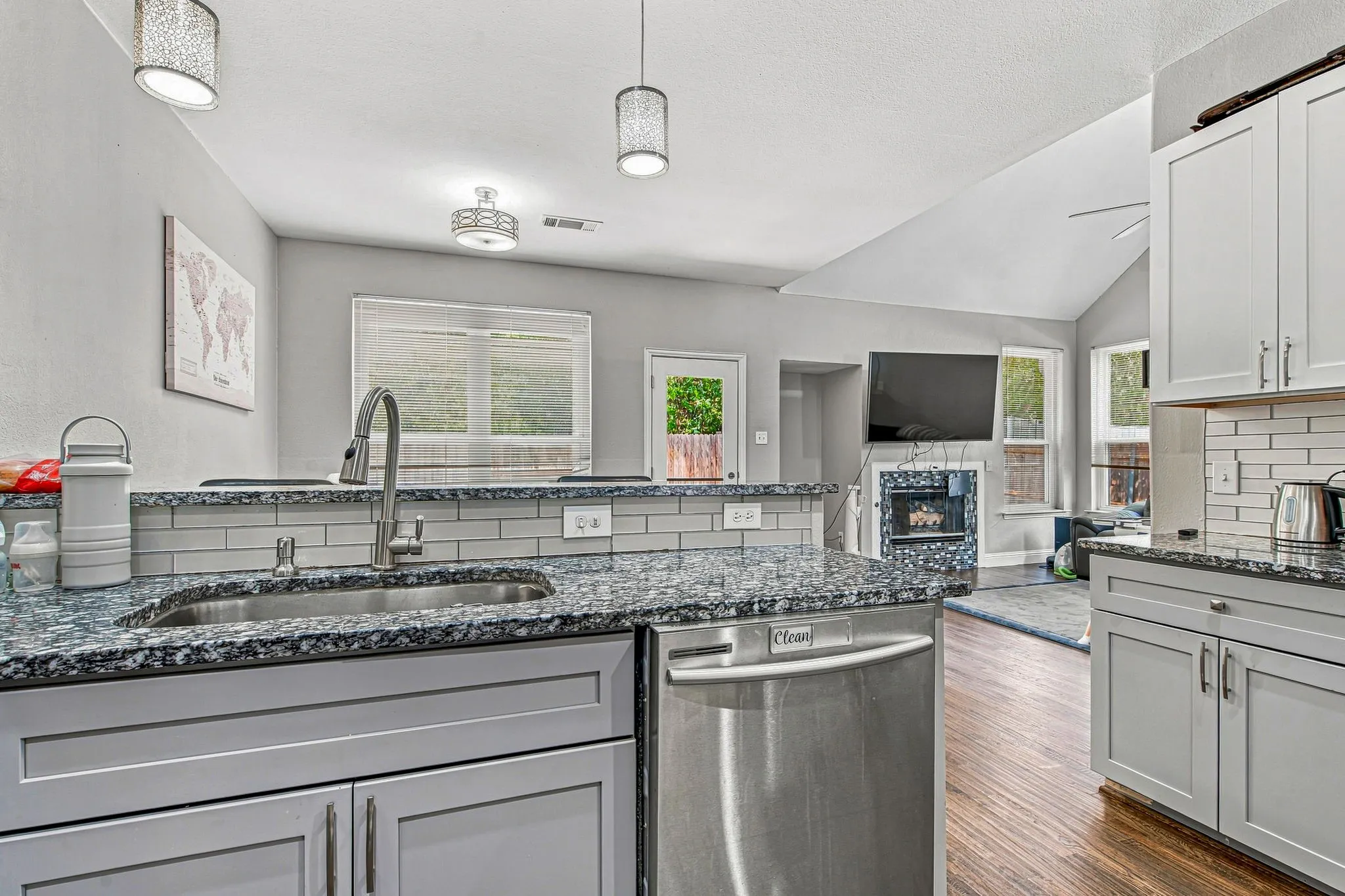 Kitchen featuring light gray cabinetry, stainless steel appliances, speckled stone countertops, and a subway tile backsplash