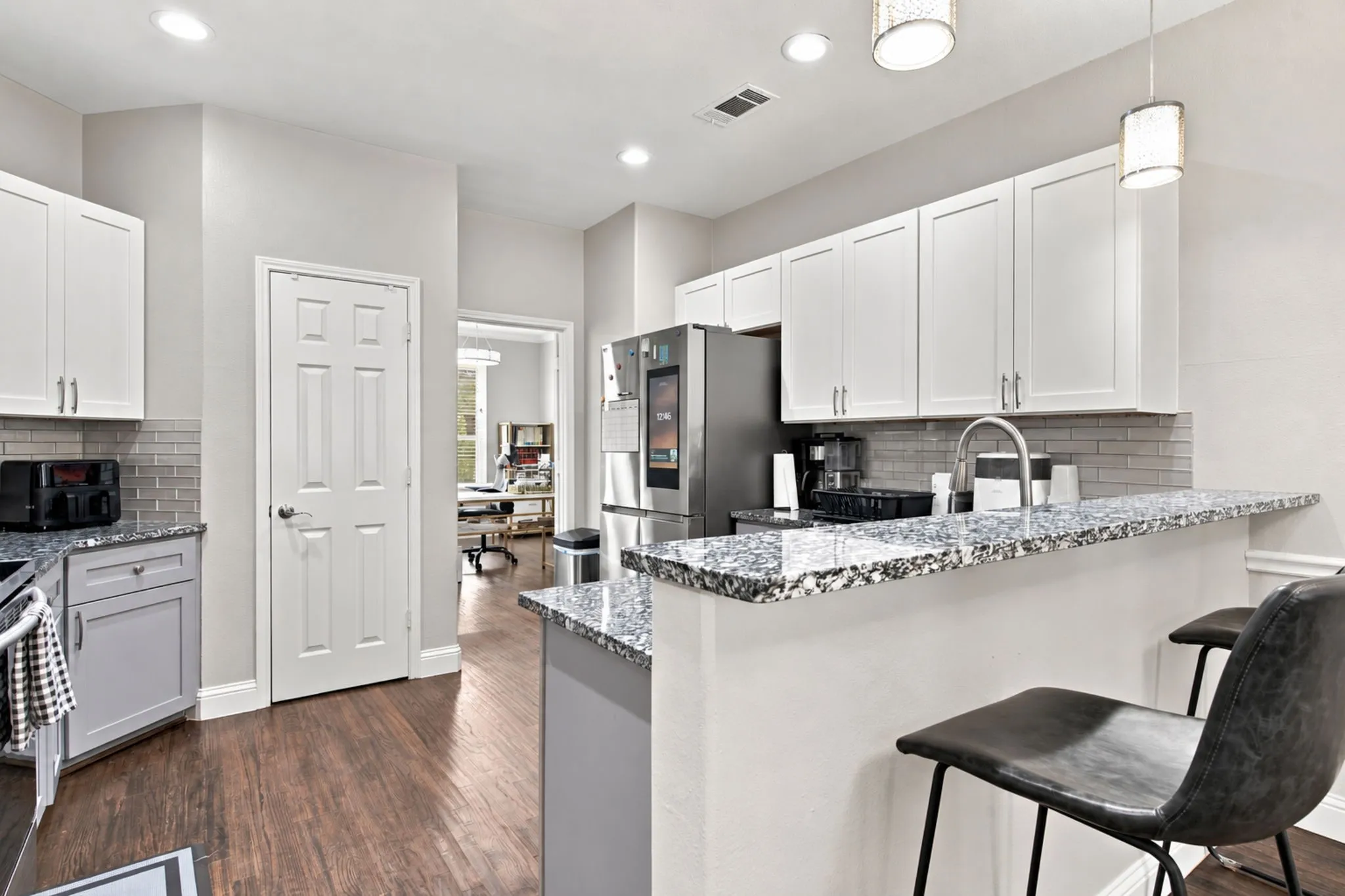 Kitchen featuring wood-finish flooring, white upper cabinetry, gray lower cabinetry, and a subway tile backsplash