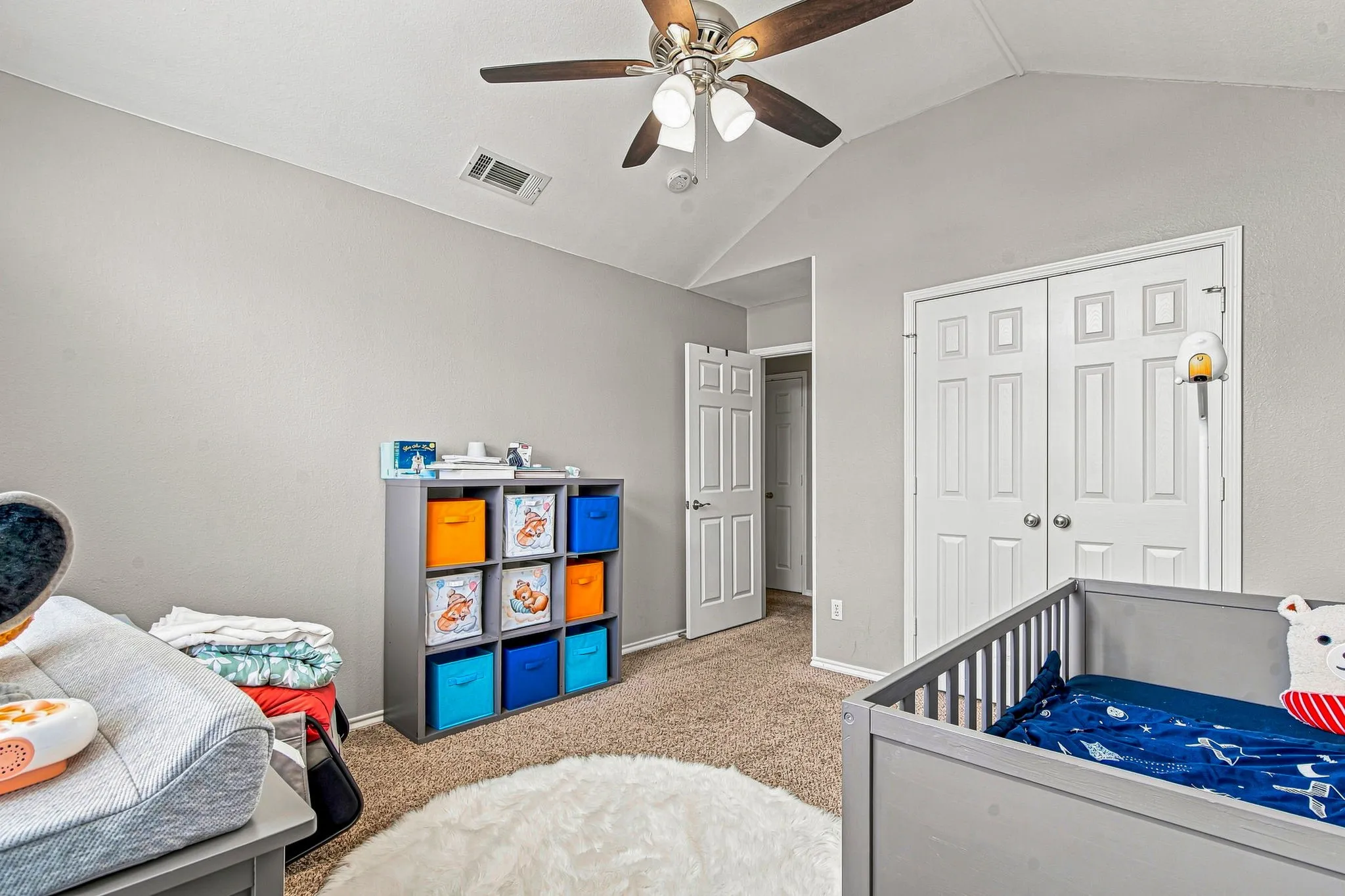 Vaulted ceiling with a ceiling fan, carpeted flooring, and a paneled closet door