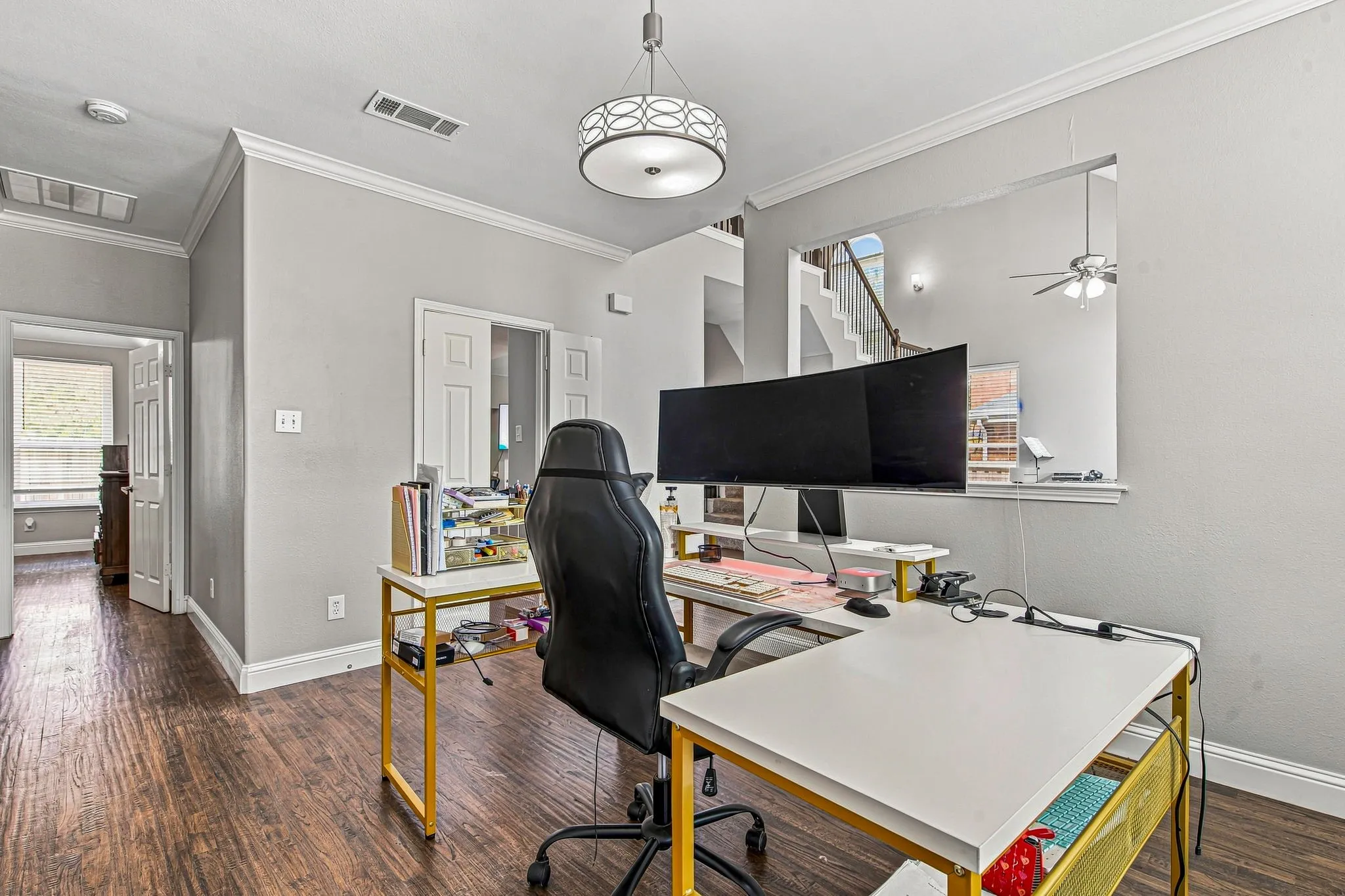 Wood-finish flooring throughout, complemented by crown molding and a contemporary drum pendant light fixture
