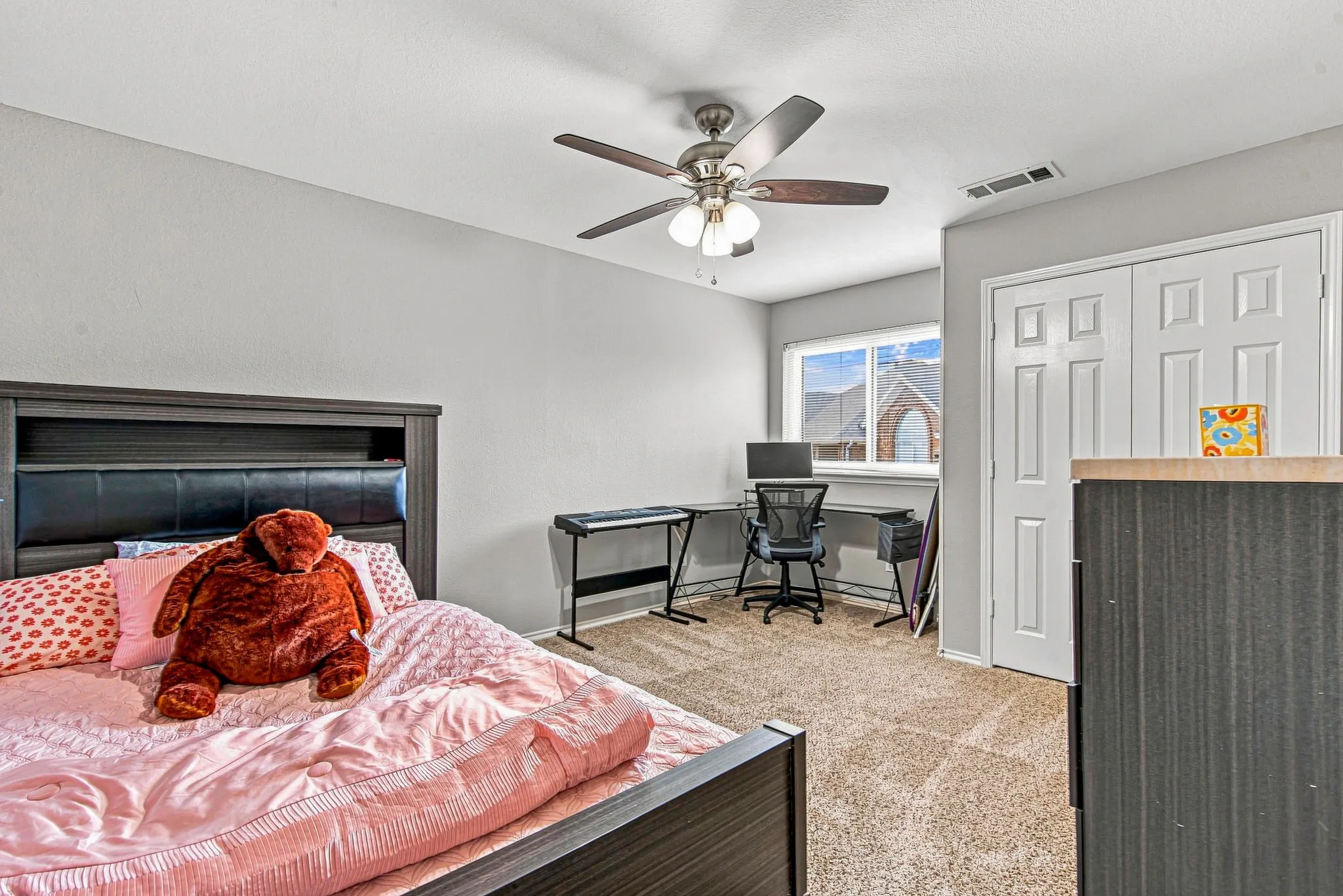 Carpeted flooring, window with exterior exposure, ceiling fan with integrated lighting, and white bi-fold closet doors