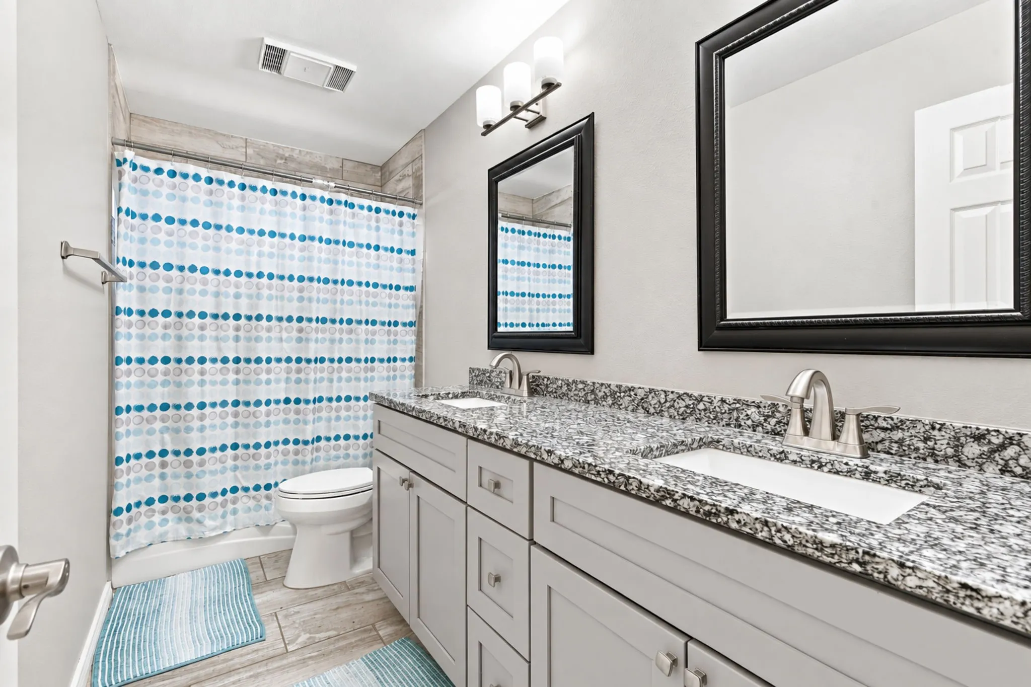 Dual vanity with integrated sinks, granite-finish countertop, and framed mirrors