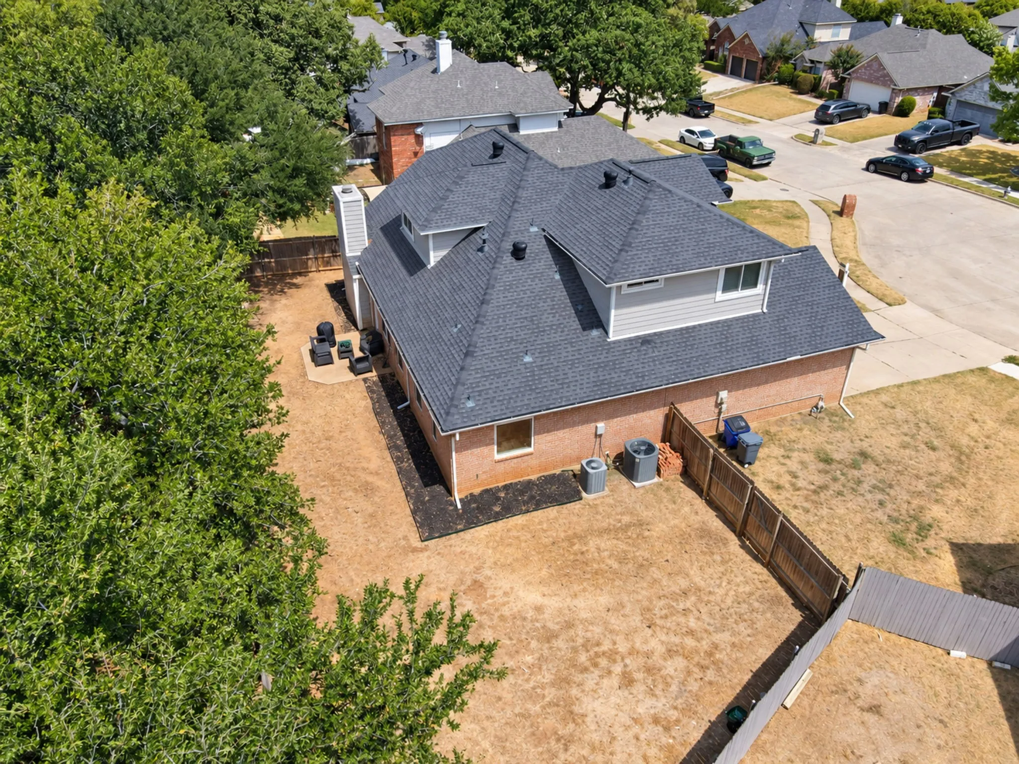 Brick exterior with a gray shingle roof and a fenced yard