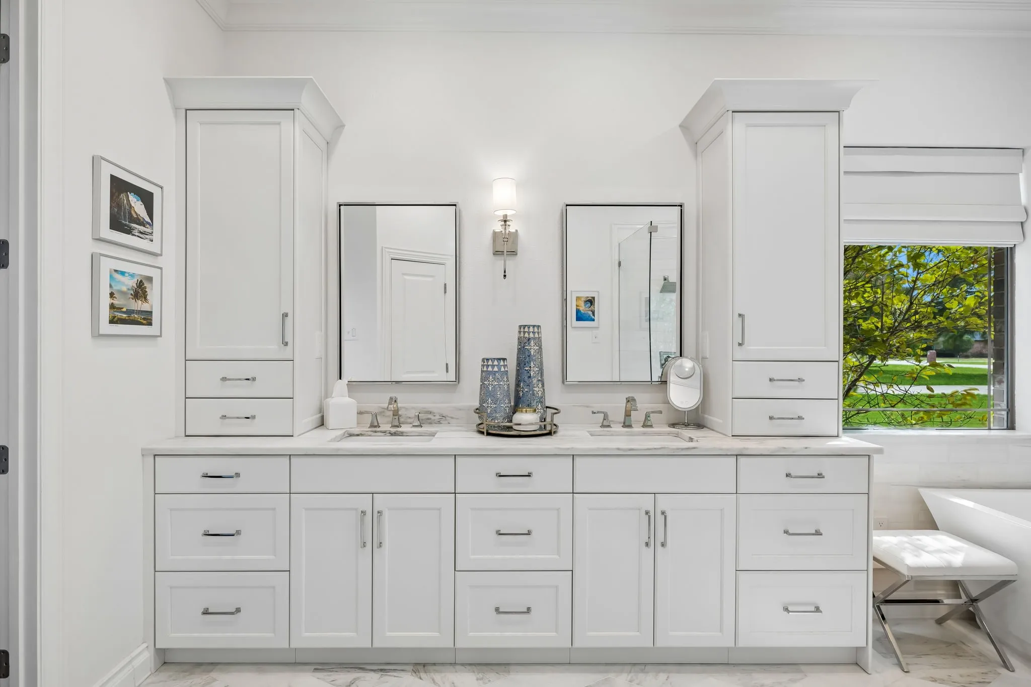 Dual sink vanity with white cabinetry, integrated storage towers, and a light-toned countertop