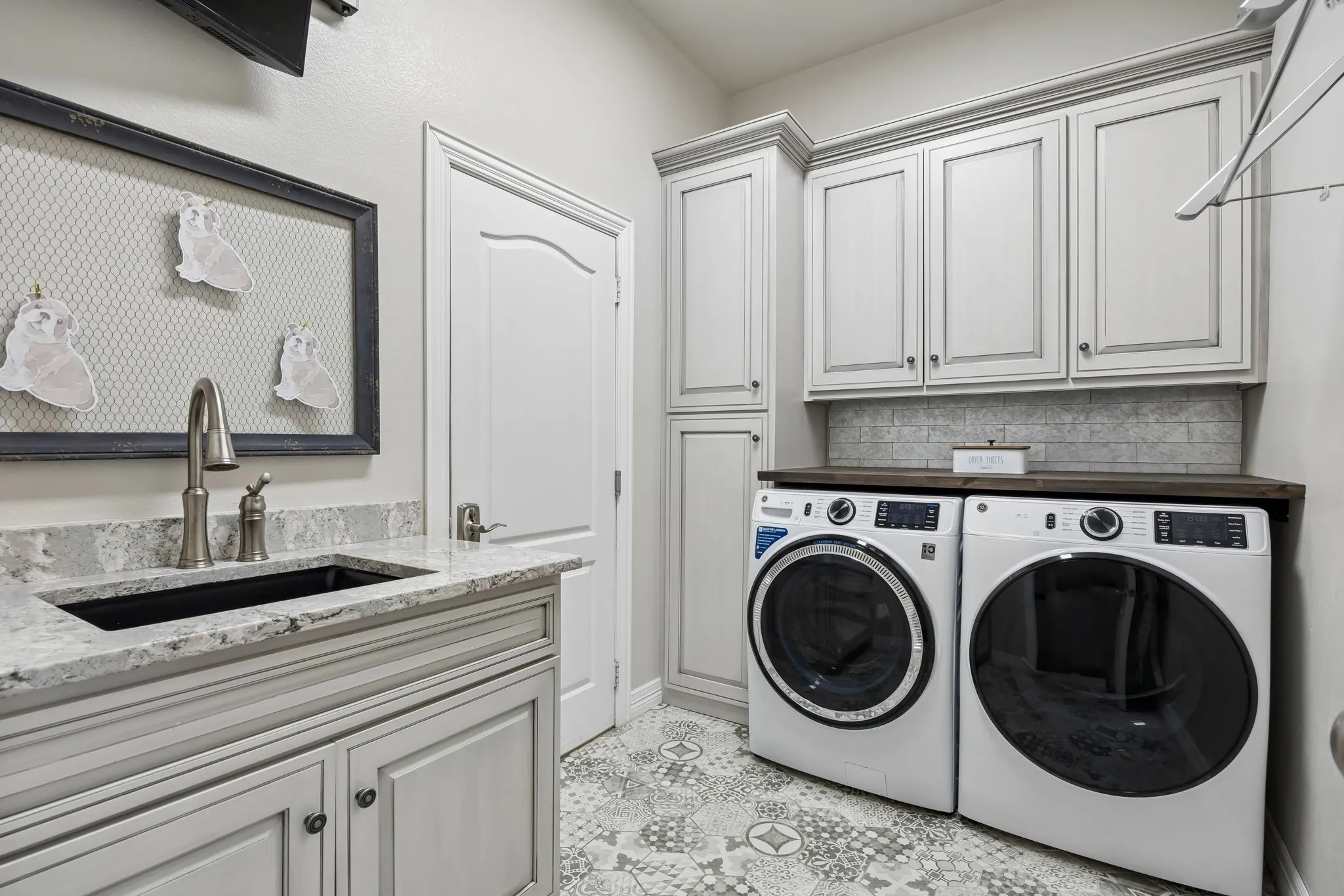 Laundry room featuring a sink, closed storage and room for a full size washer and dryer.