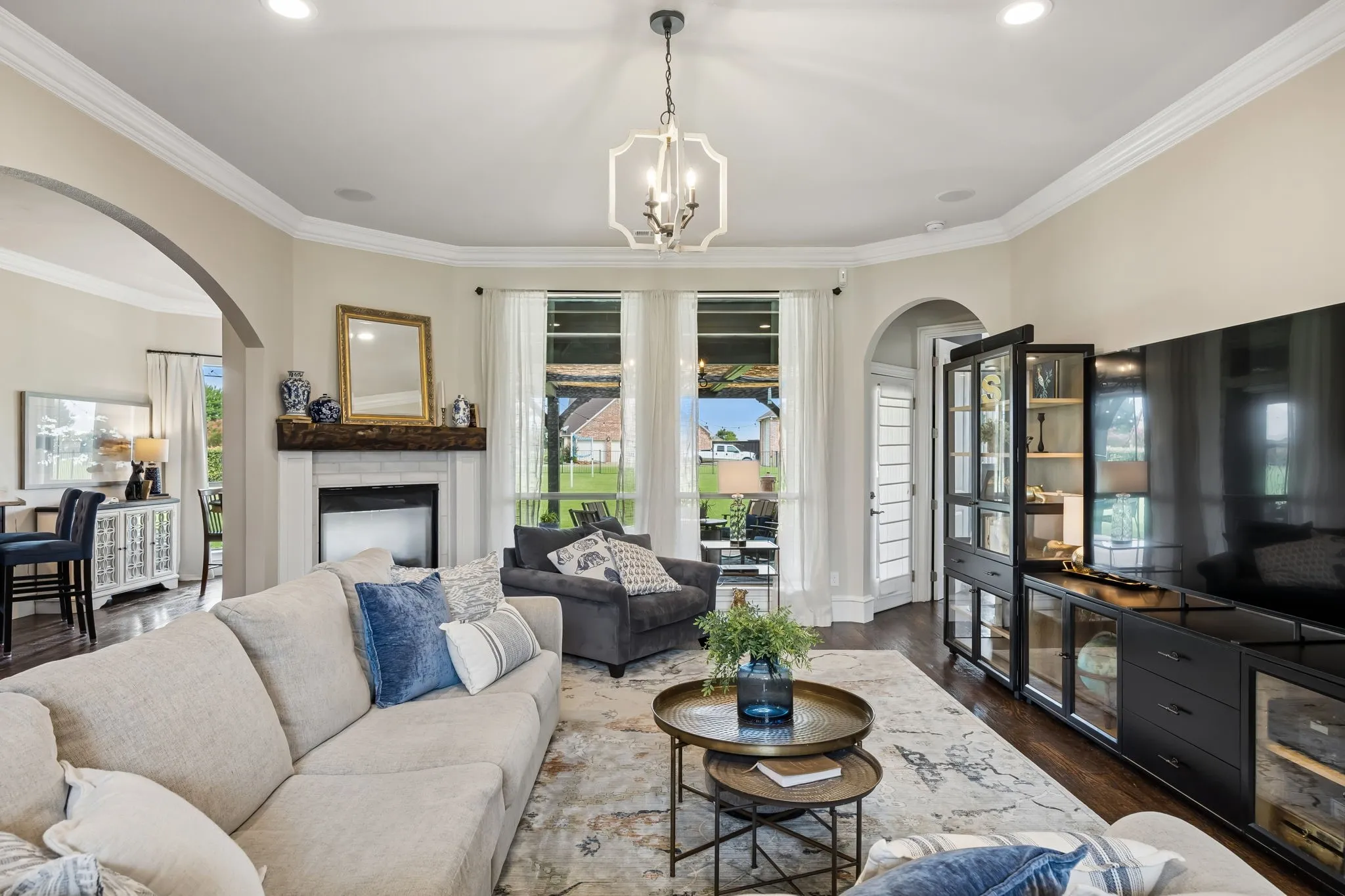 Spacious living area featuring a fireplace with a wood beam, arched doorways and a view of the backyard