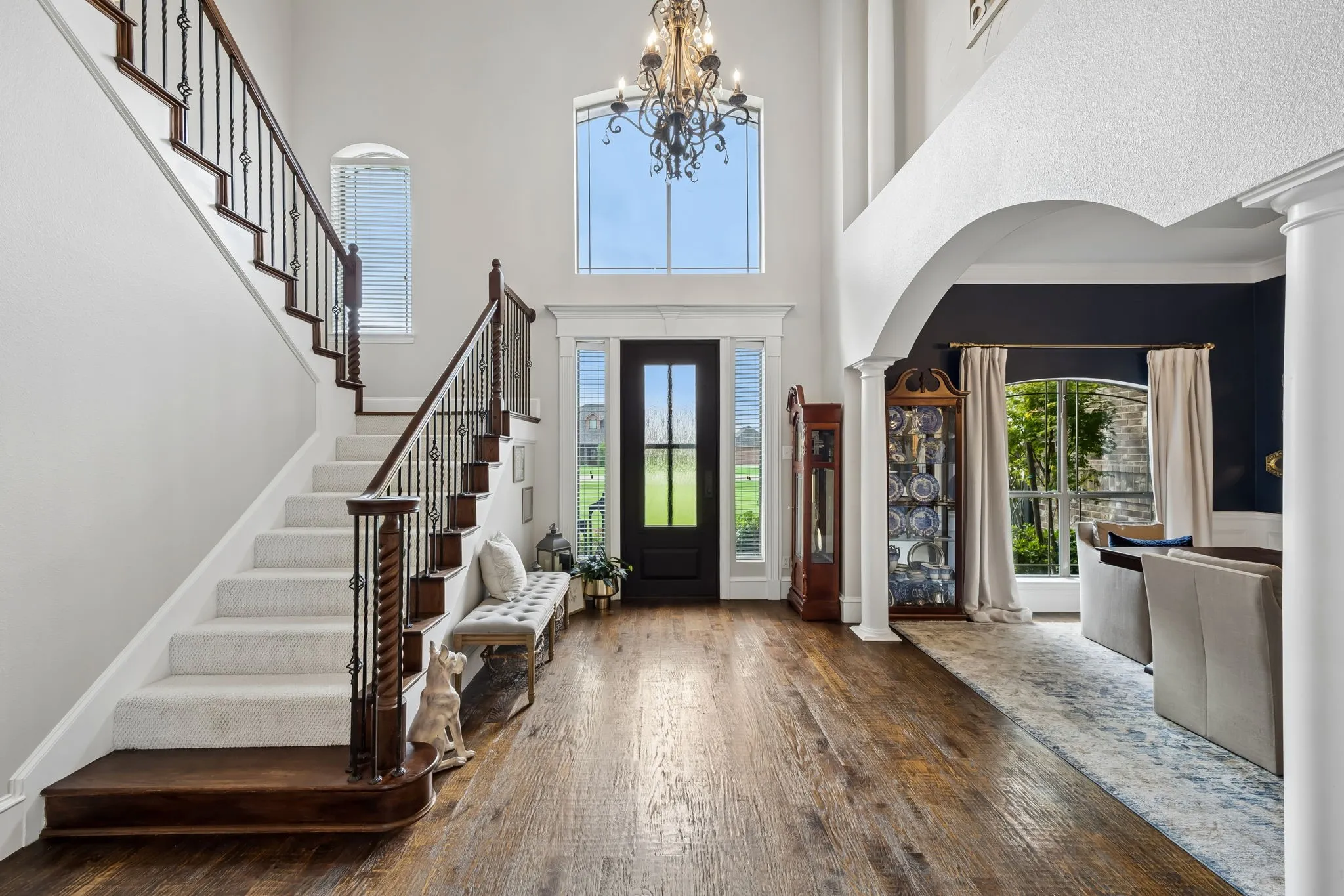 Grand foyer featuring wood-finish flooring and a staircase with wrought iron balusters