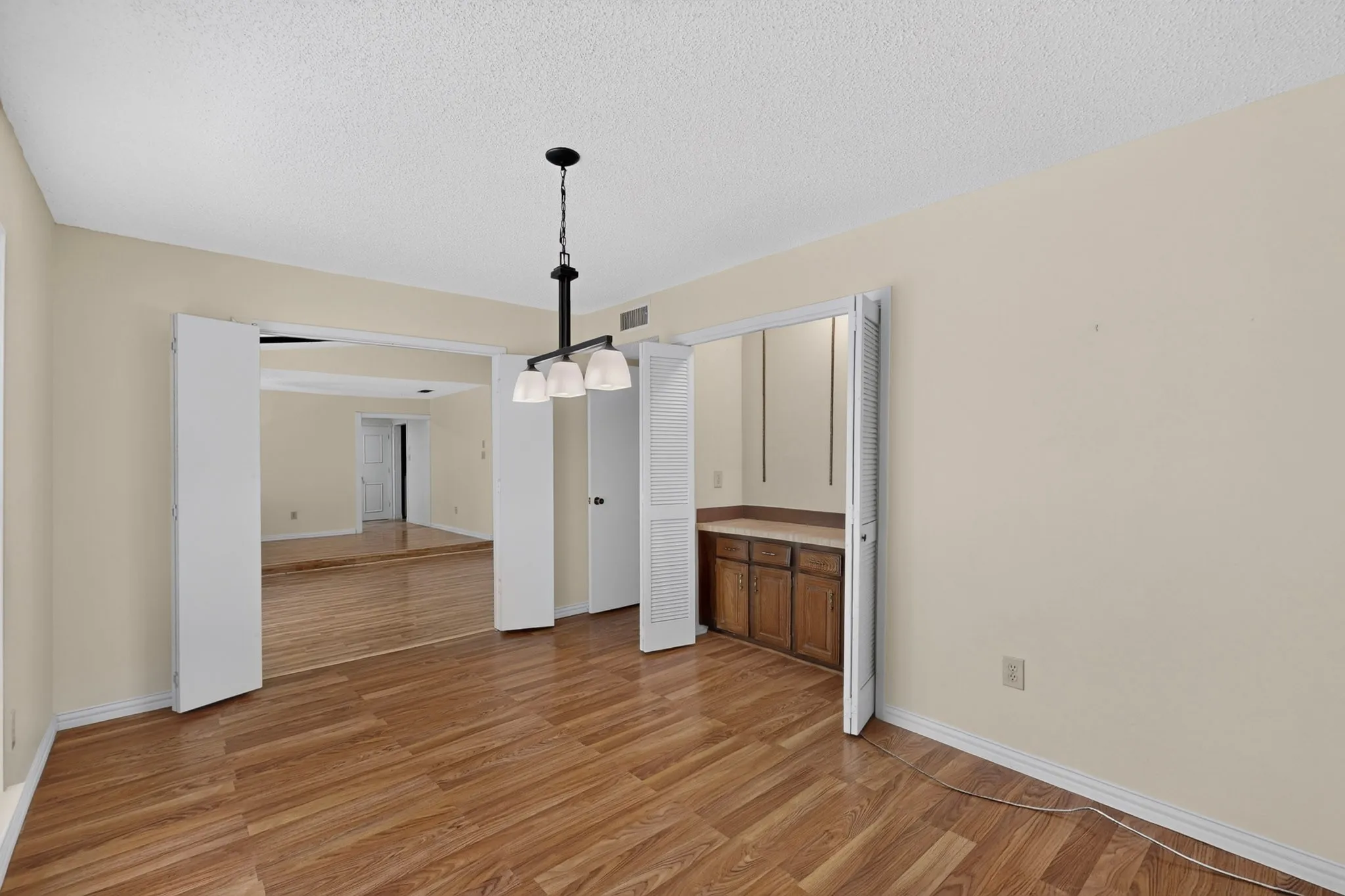 Wood-finish flooring throughout, with a recessed built-in wet bar featuring wood cabinetry and a counter