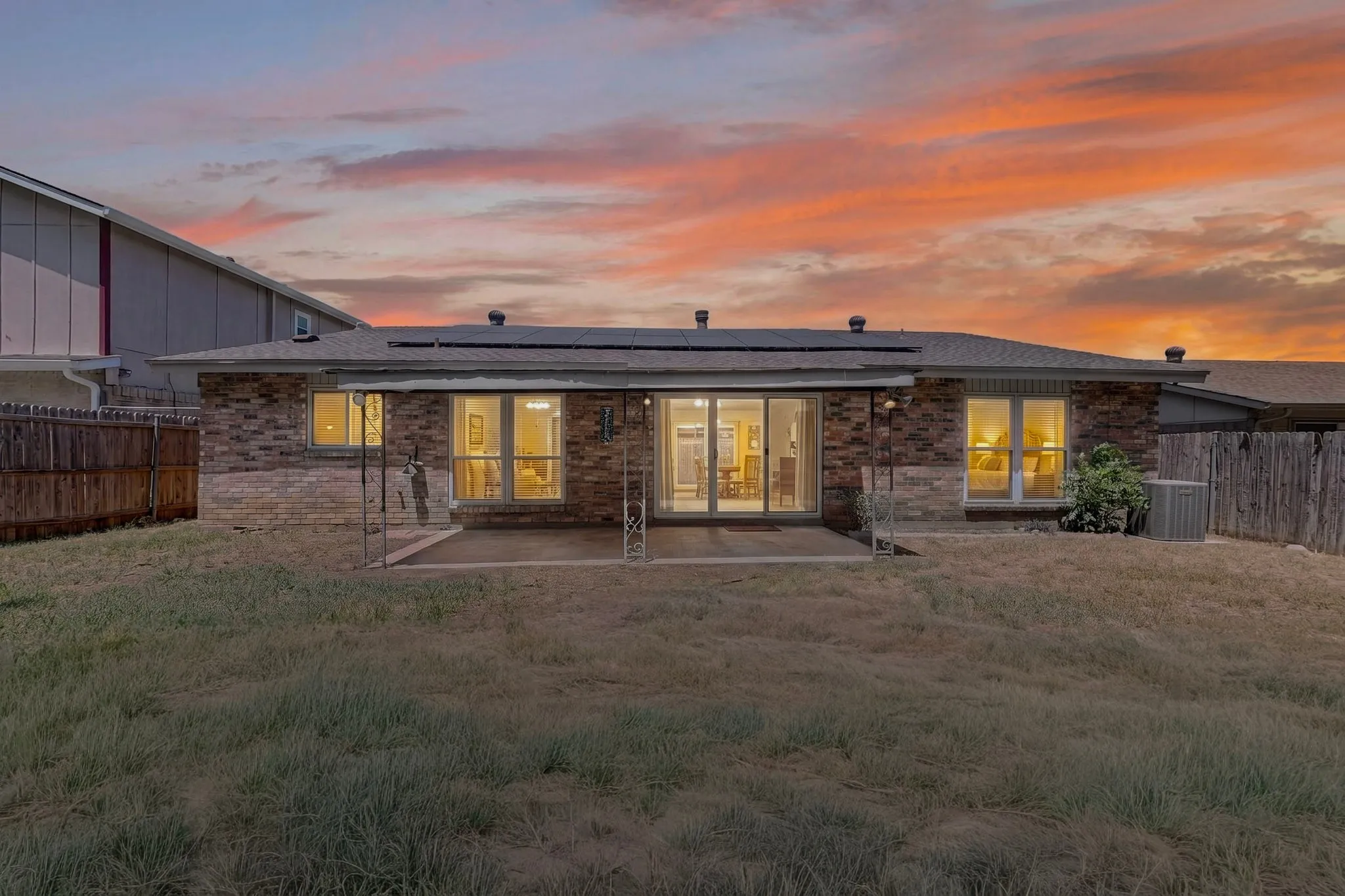 Brick exterior with an extended patio, sliding glass doors, and multiple windows