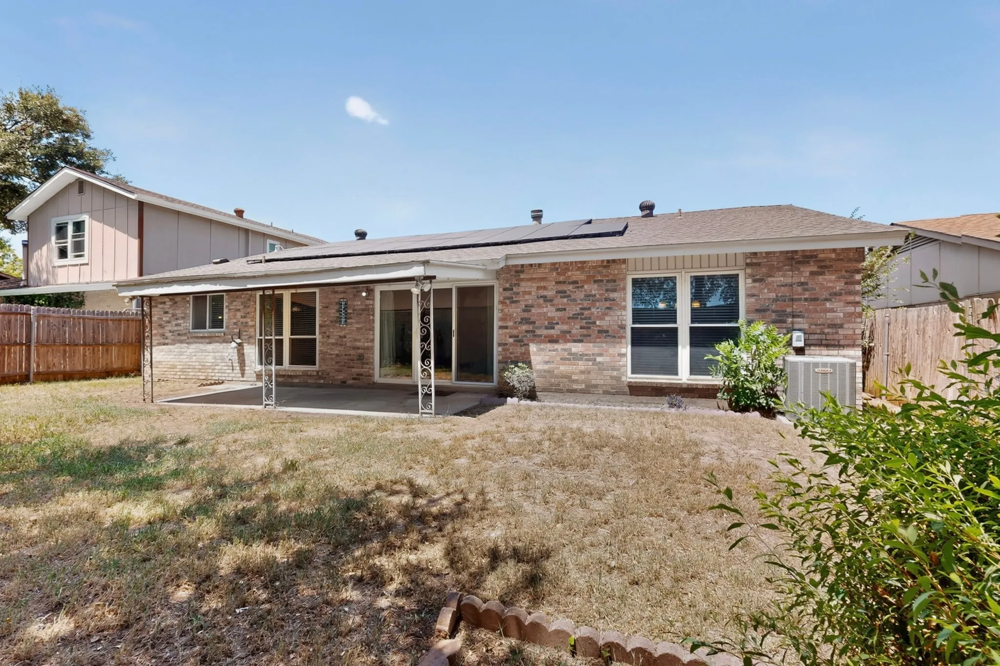 Brick exterior with a covered patio, sliding glass doors, and solar panels