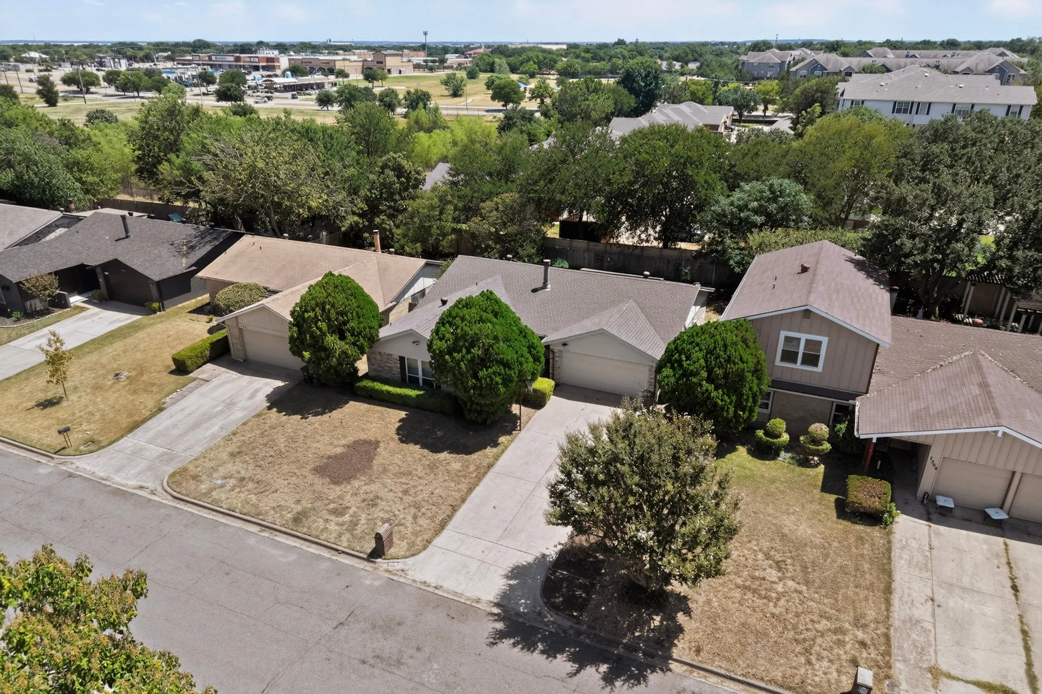 Single-story residence with an attached two-car garage, mature front yard trees, and a concrete driveway
