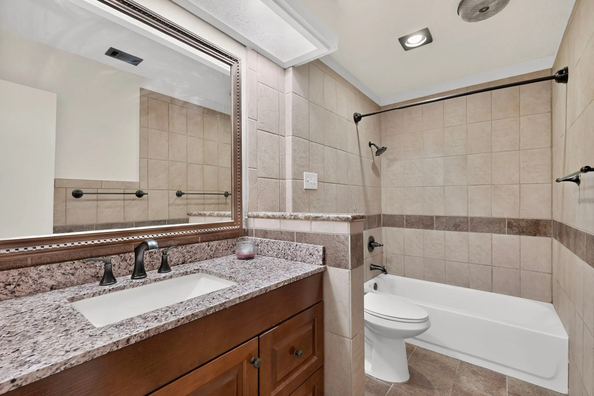 Bathroom featuring a vanity with a granite countertop, undermount sink, and dark wood-finish cabinetry