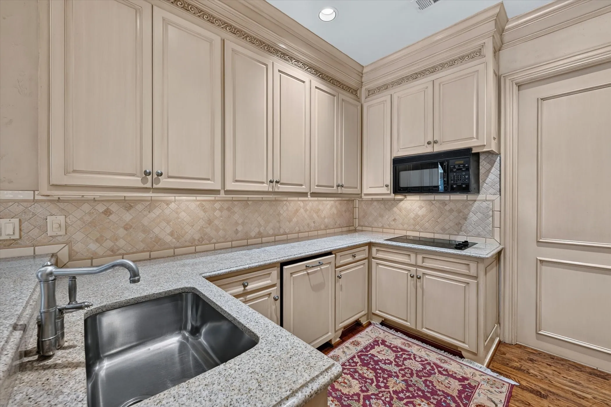 Kitchen has tumbled marble backsplash, stone counters & wood floors.
