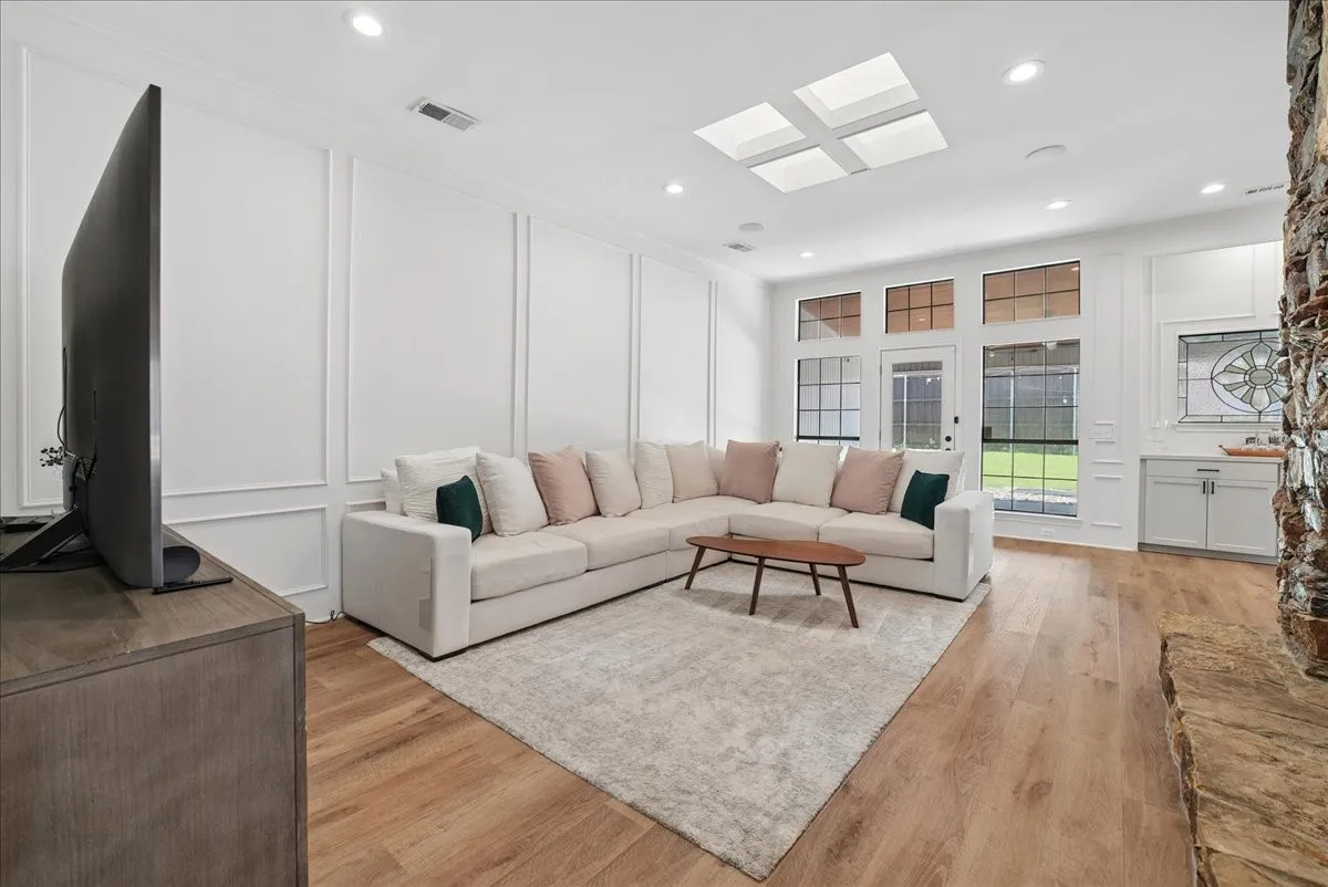 Spacious living area featuring wood-finish flooring, white wainscoting, and recessed lighting