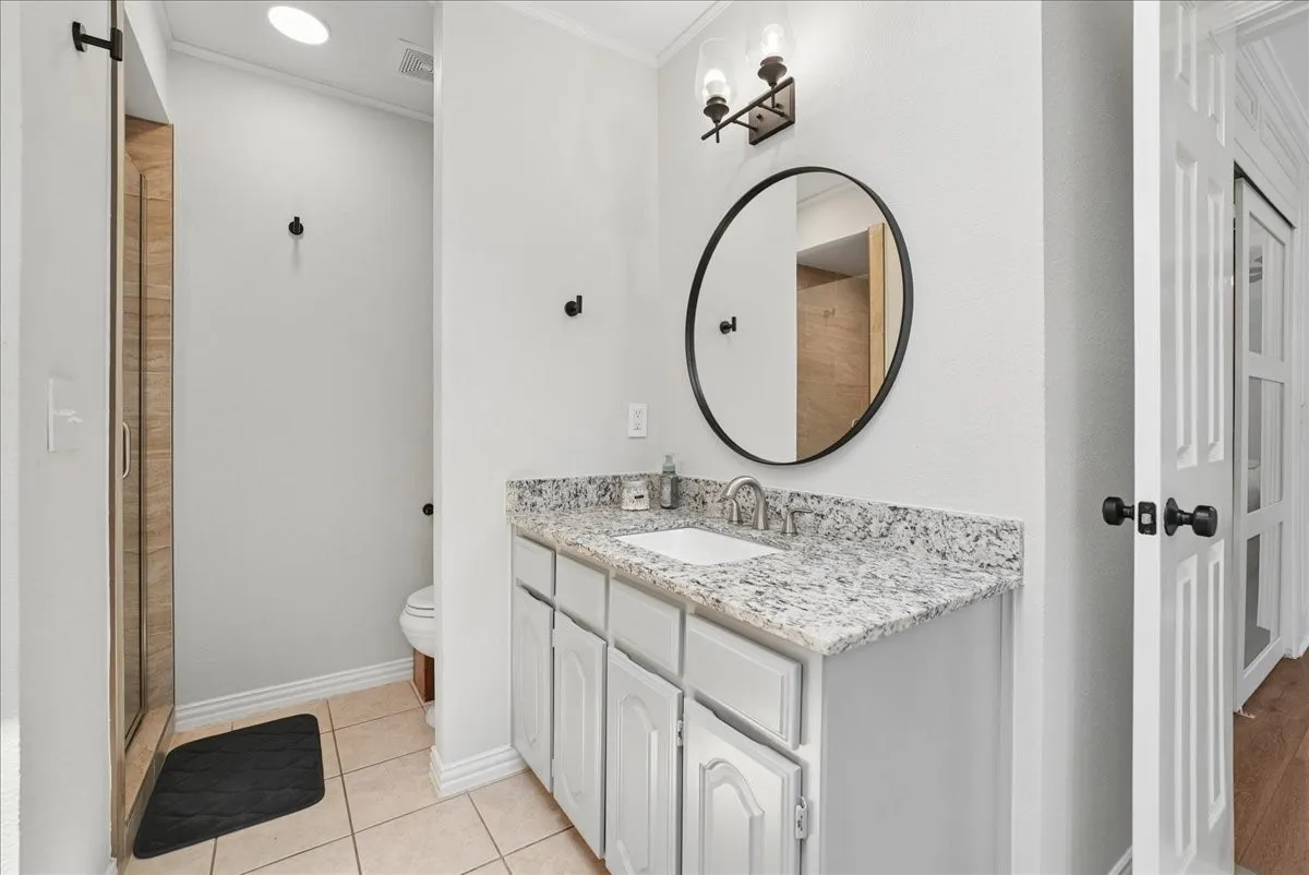 Bathroom vanity featuring a granite countertop, undermount sink, and brushed nickel faucet