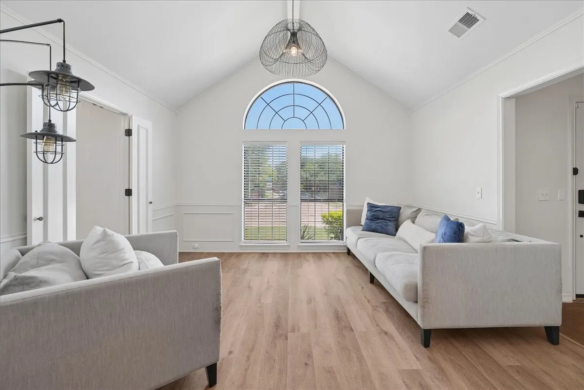 Vaulted ceiling with a large arched window and wood-finish flooring