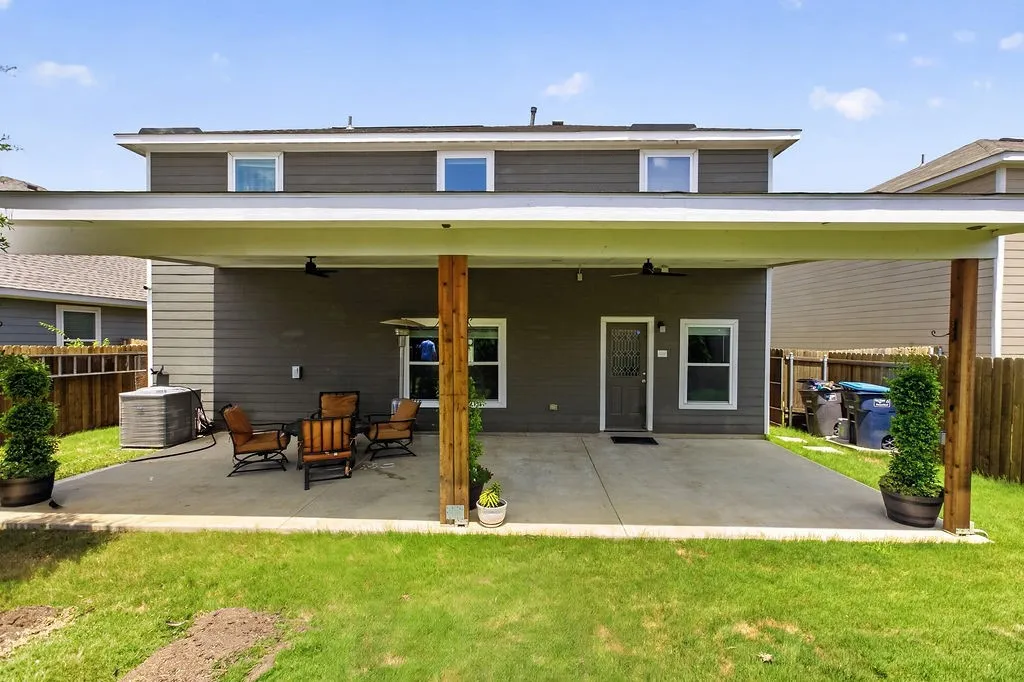 Covered patio with concrete flooring, wood posts, and two ceiling fans