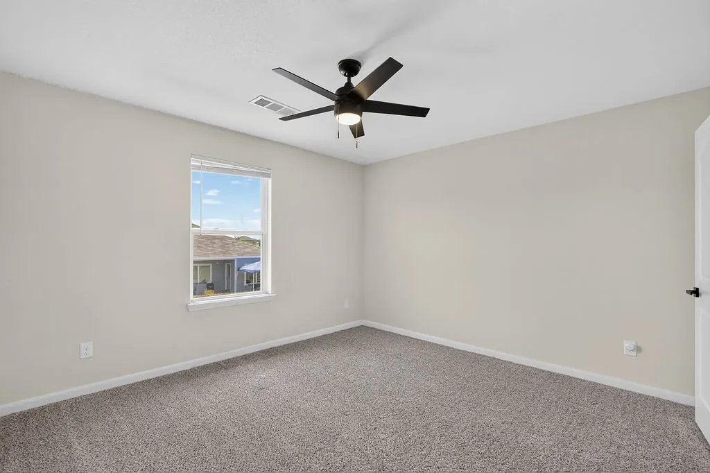 Carpeted room with a ceiling fan featuring integrated lighting, a single window with blinds, and neutral wall paint