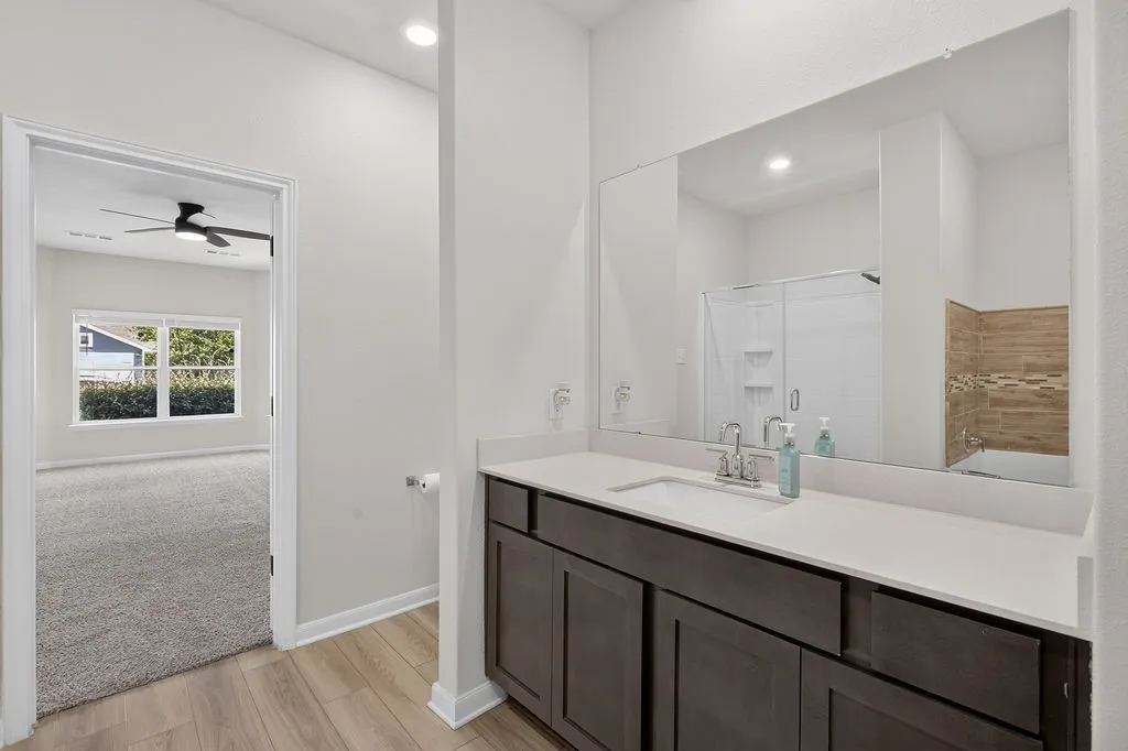 Bathroom featuring wood-finish flooring and an expansive vanity with a light-toned countertop and integrated sink