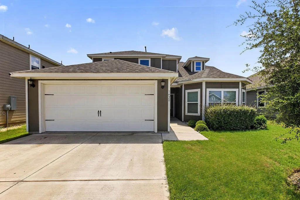 Contemporary two-story exterior with a two-car garage, concrete driveway, and a front walkway leading to the entrance