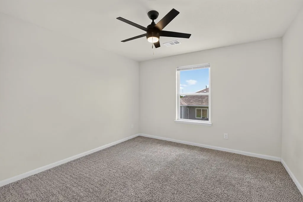Carpeted interior room featuring light-toned walls and a ceiling fan with integrated lighting