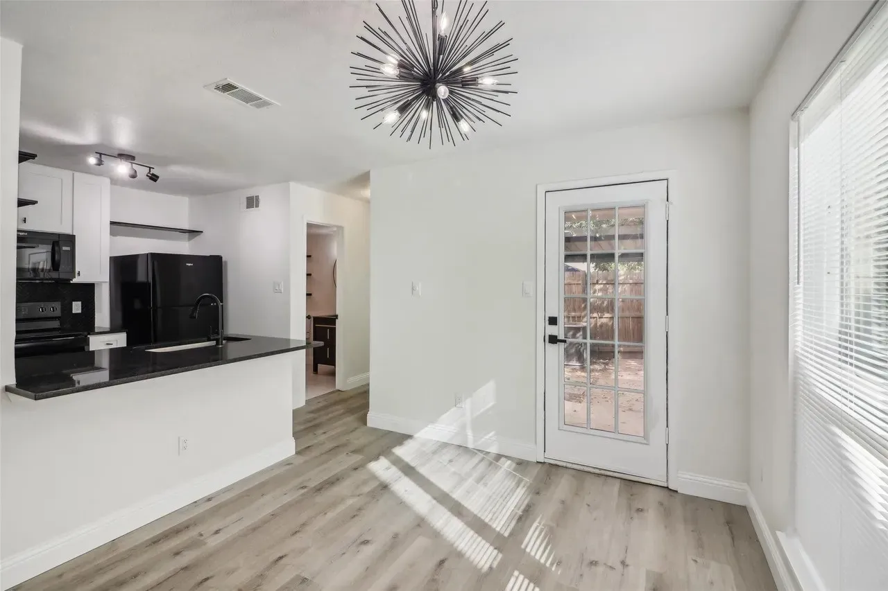 Open-concept living space featuring wood-finish flooring, a contemporary sputnik chandelier, and a kitchen bar with a dark countertop